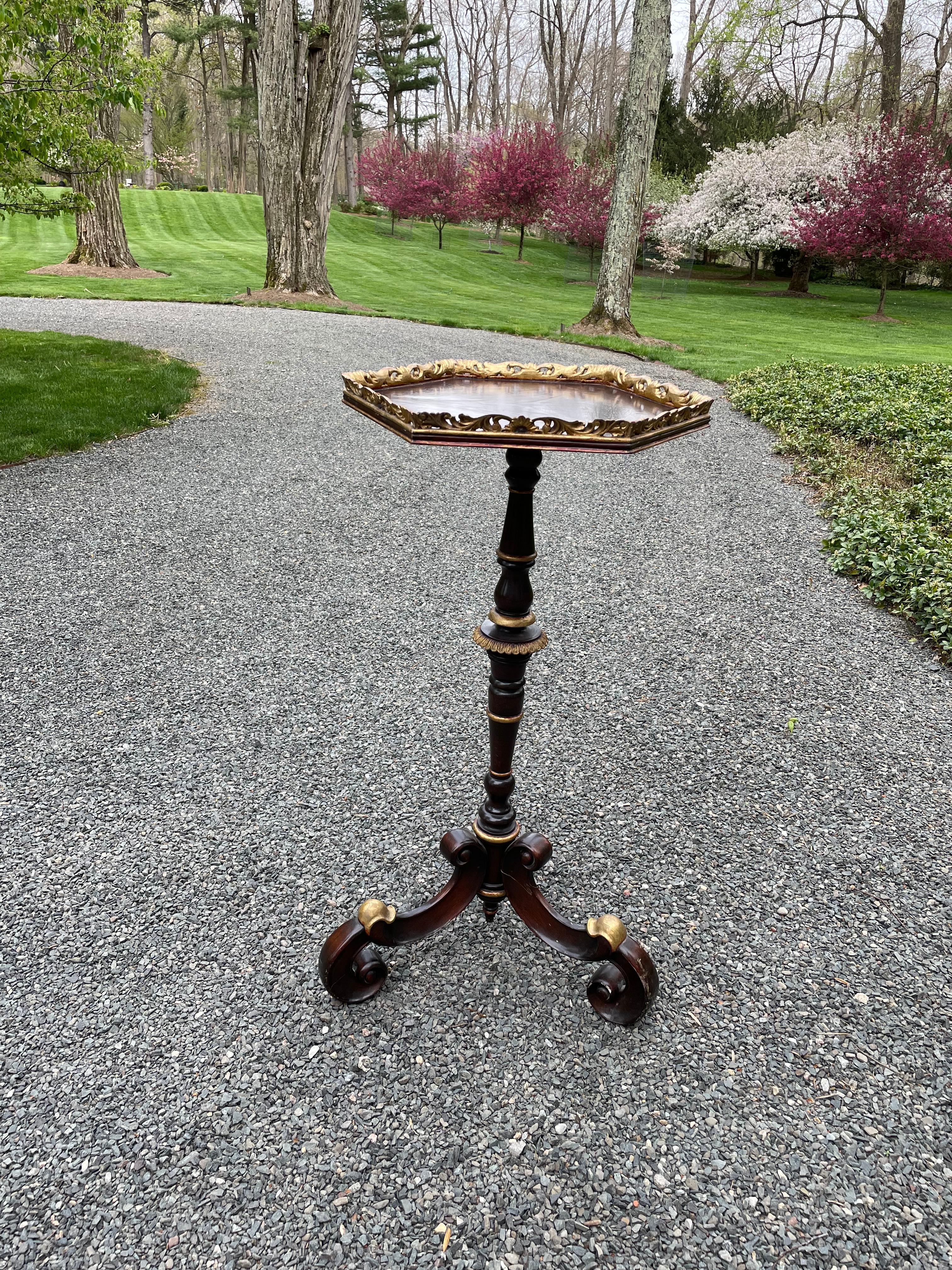 Lovely mahogany octagonal shaped plant Stand having gilded gallery and elaborate scrolled base. Some of the base has gilded embellishment as well.