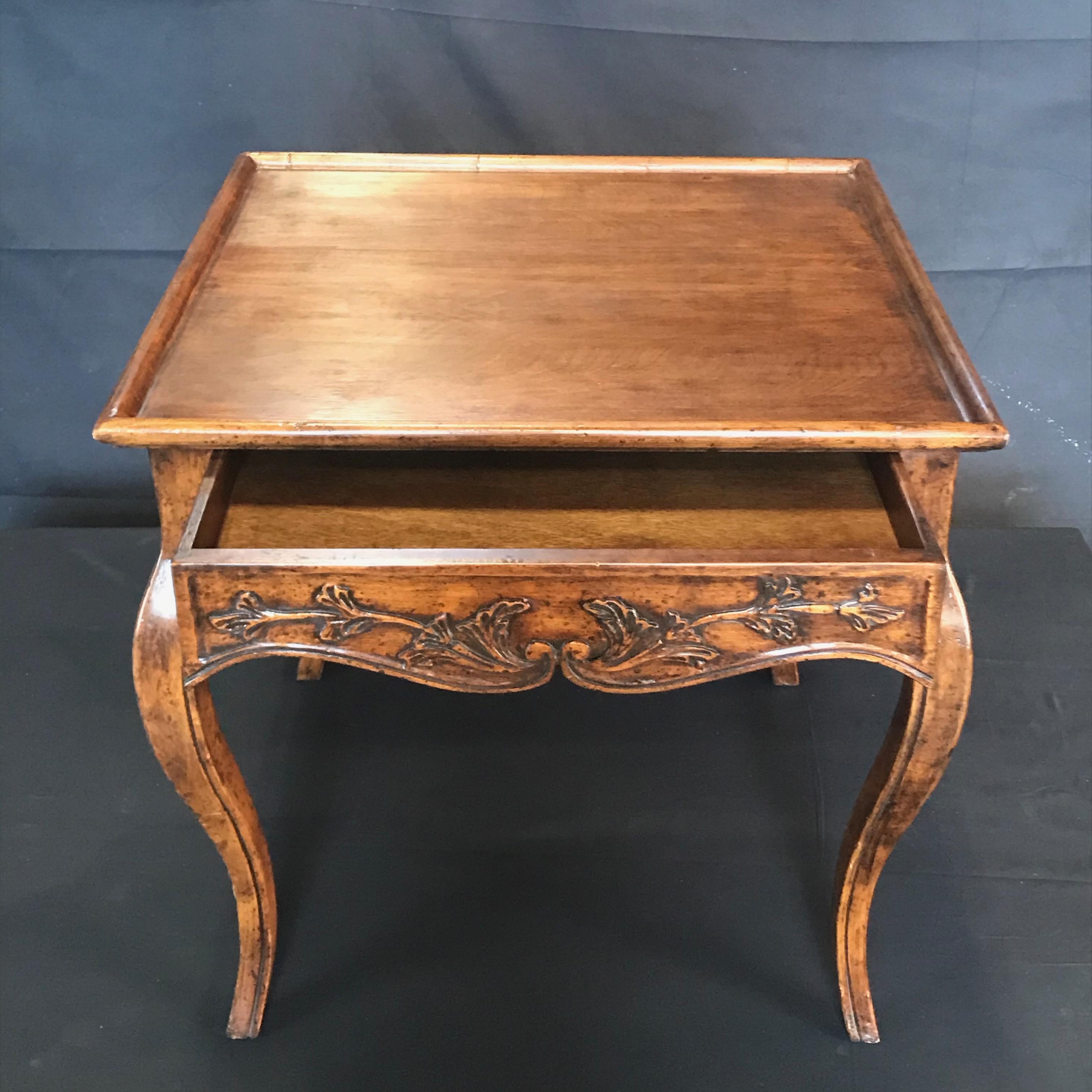 An Italian Régence or Louis XV style walnut side table from the early 20th century having one drawer, cabriole legs and carved foliage apron 19.75 from floor. Created in Northern Italy, this lovely side table features a square inset galleried top