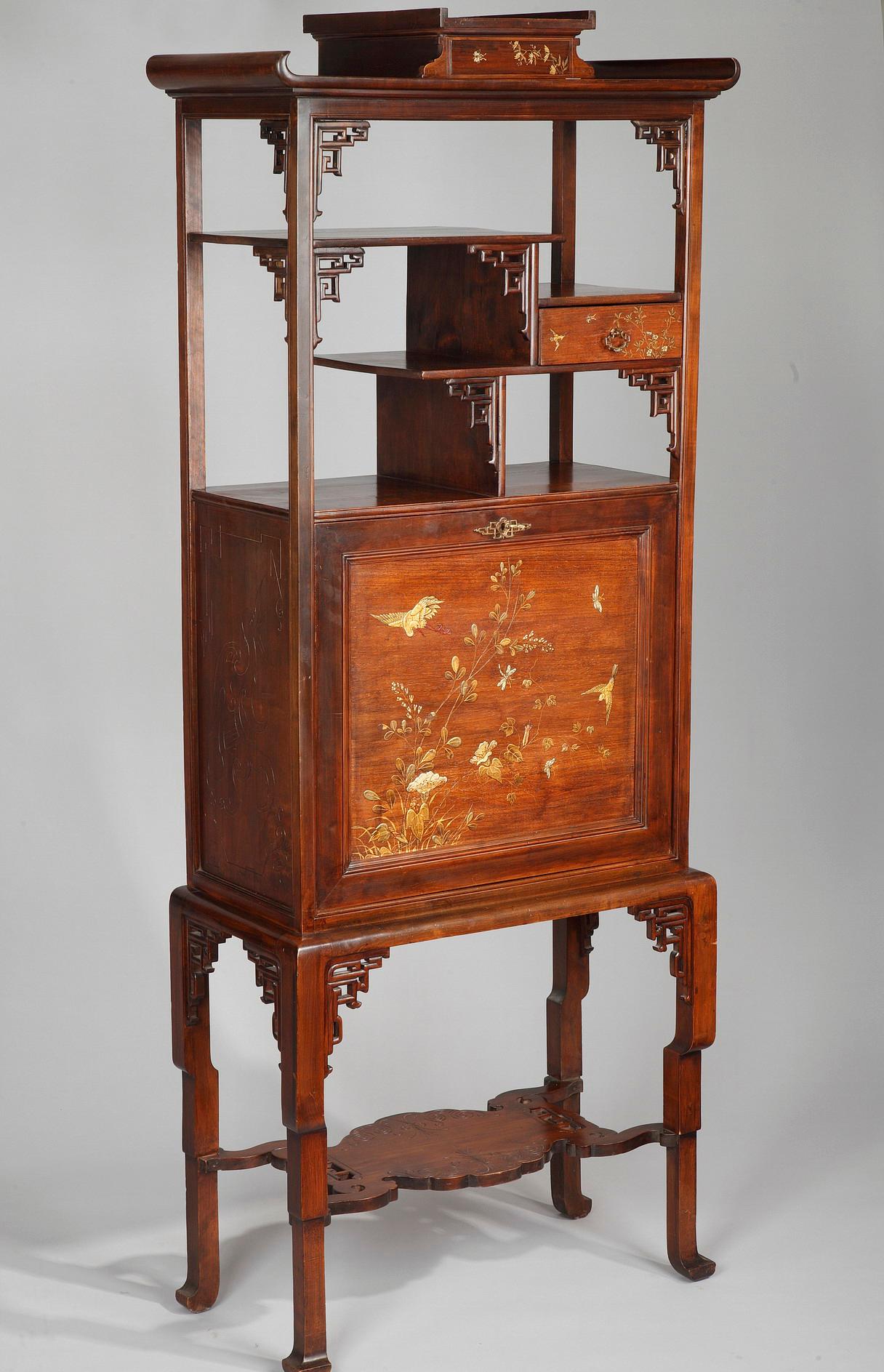 A Japanese style carved wood cabinet attributed to G. Viardot. A painted decor imitating Japanese lacquer, ornamented with flowers, birds and butterflies. Opening onto two drawers and a paper filer, the upright-secretary door is also fitted with red
