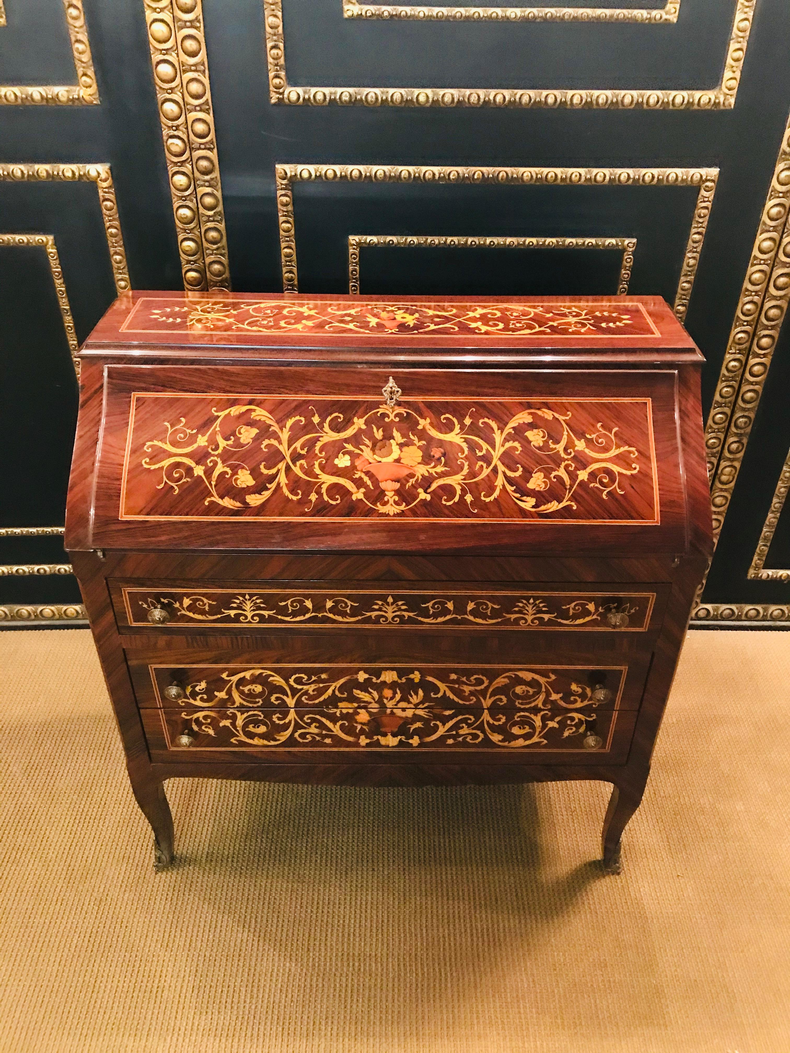 A very beautiful, elegant ladies secretary in the Italian style, the 20th century. Rosewood veneer and various precious woods, floral inlay, high-gloss lacquered body with three drawers on slightly curved legs, inside with various compartments