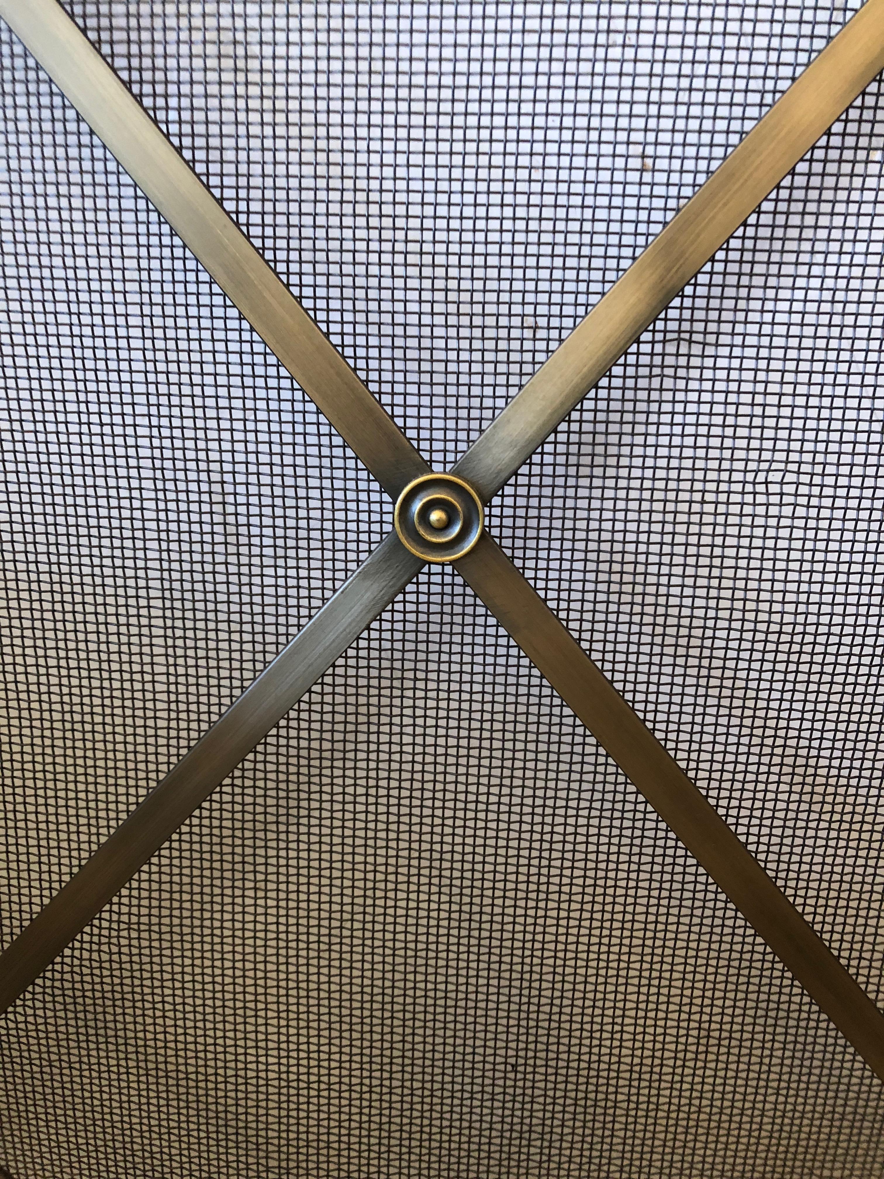 Beautiful brass and iron mesh mid-century modern fireplace screen in bronzey gold color, having the criss cross pattern in the manner of Jean Royère.