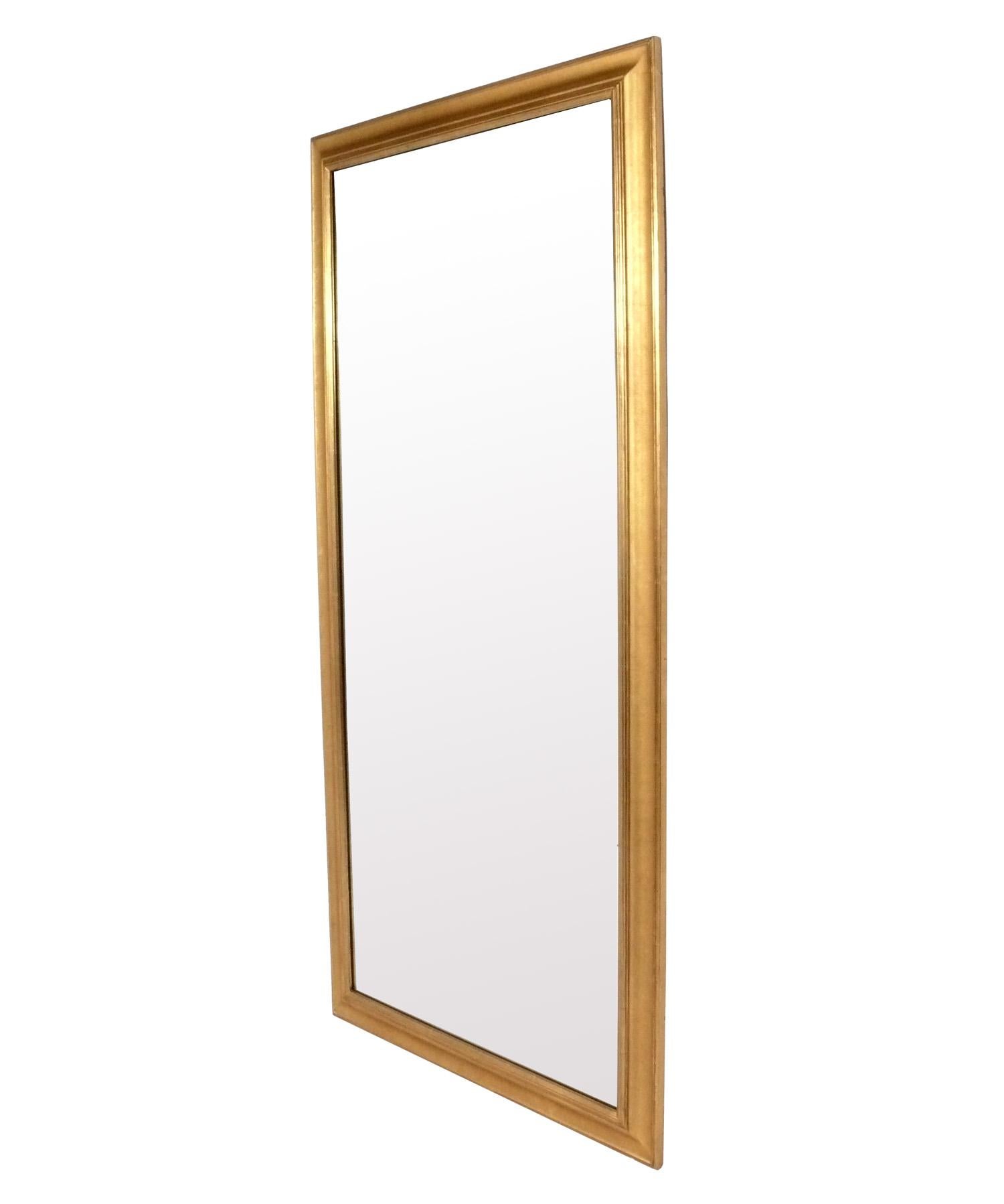 Elegante espejo dorado de grandes dimensiones, estadounidense, hacia la década de 1960. Mide unas impresionantes 80