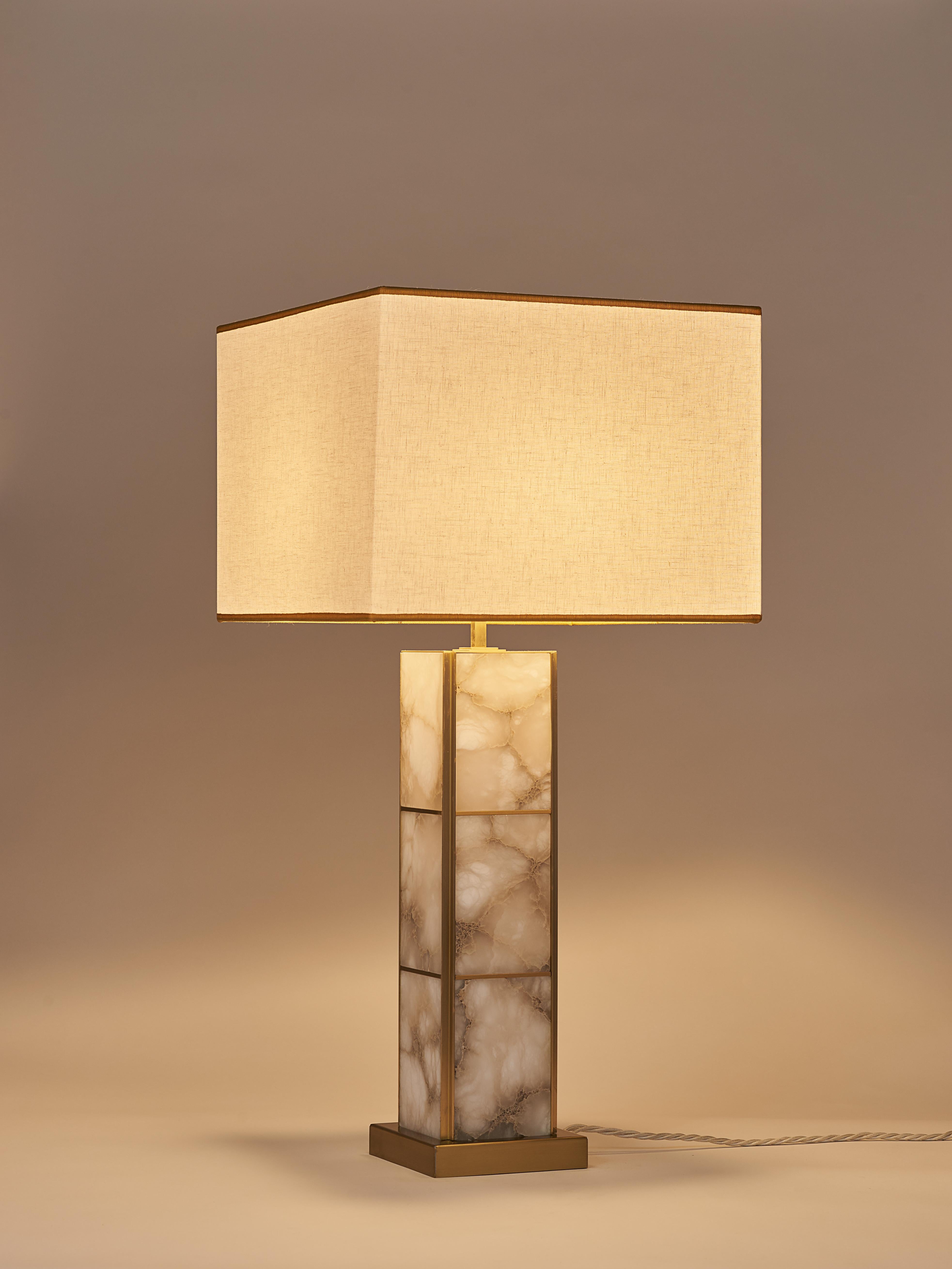 The Mole table lamp is characterized by a monolithic linear structure in brass and veined alabaster which gives it a modern and timeless aesthetic, perfect for different interior styles. Satin brass adds a touch of sophistication and warmth, while
