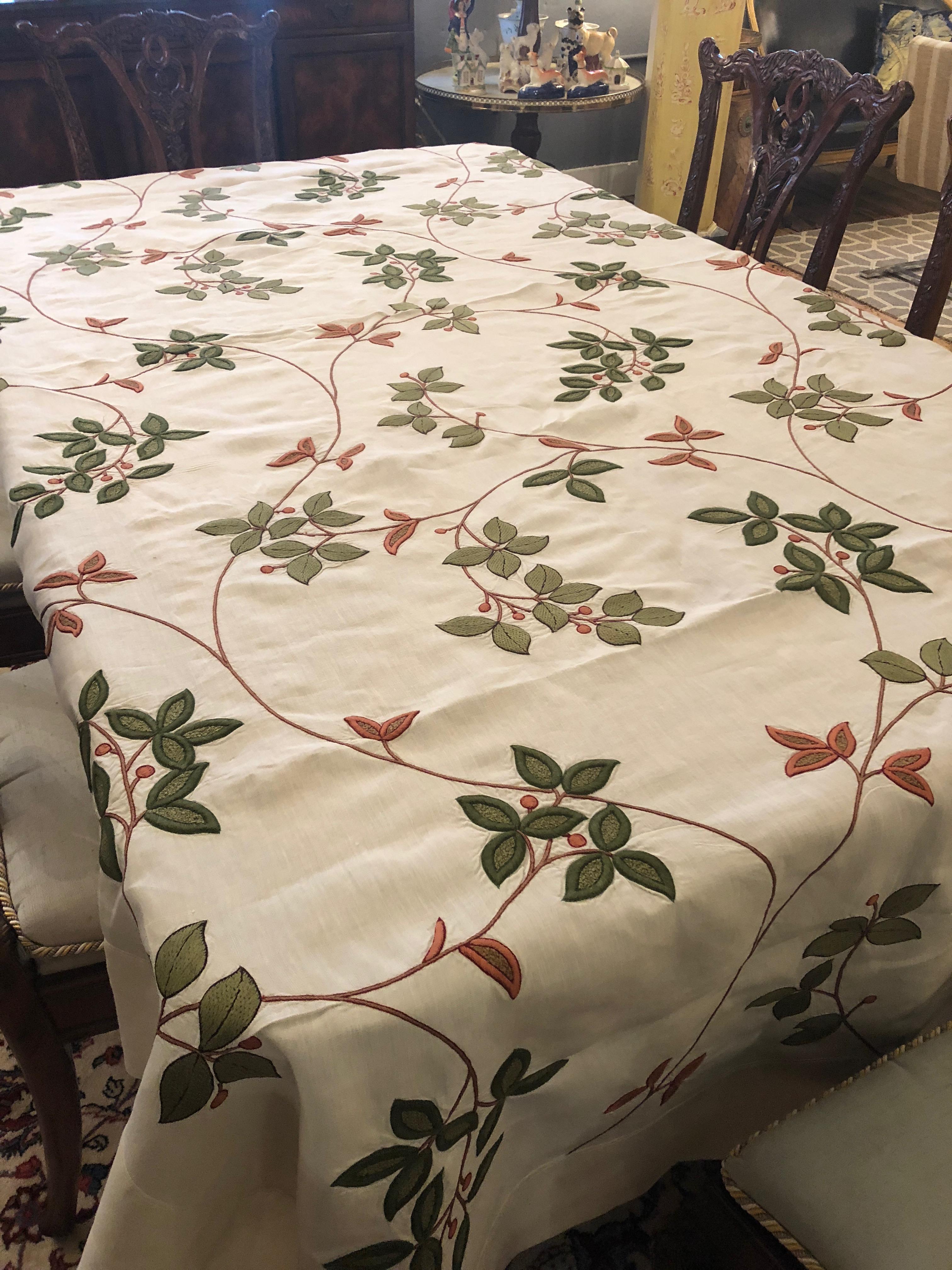 Lovely large cream colored linen tablecloth having green and terracotta leaves and flowers embroidered on it.