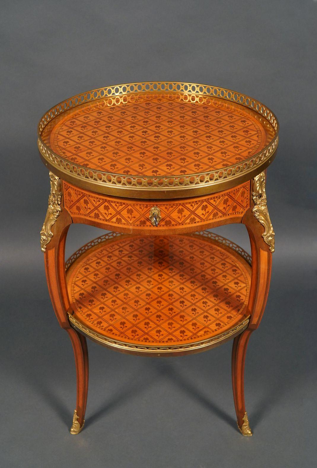 
Very fine Louis XV Style guéridon in green-stained wood marquetry , with fine ornamentation in chiseled and gilded bronze, opening with a drawer on the belt.
The tray top and the undershelf are surrounded by a gilded bronze openwork gallery and