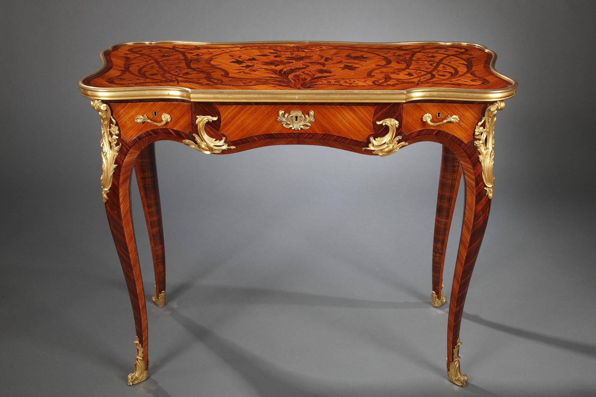 Charming Louis XV style table by Sormani, opening with three drawers. The waved rectangular tray, adorned with a floral bois-de-bout marquetry, is circled by a gilded bronze mold. It rests on four cabriole legs surmounted by a gilt-bronze mount and