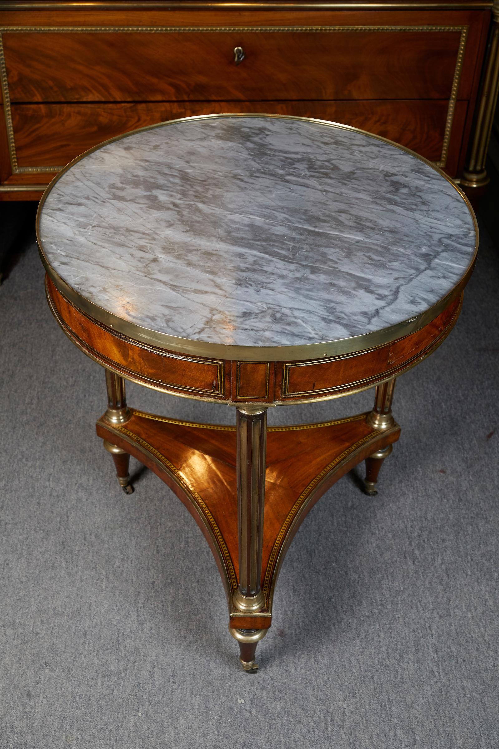 Elegant mahogany Louis XVI period gueridon with grey St Anne marble top resting on castors.