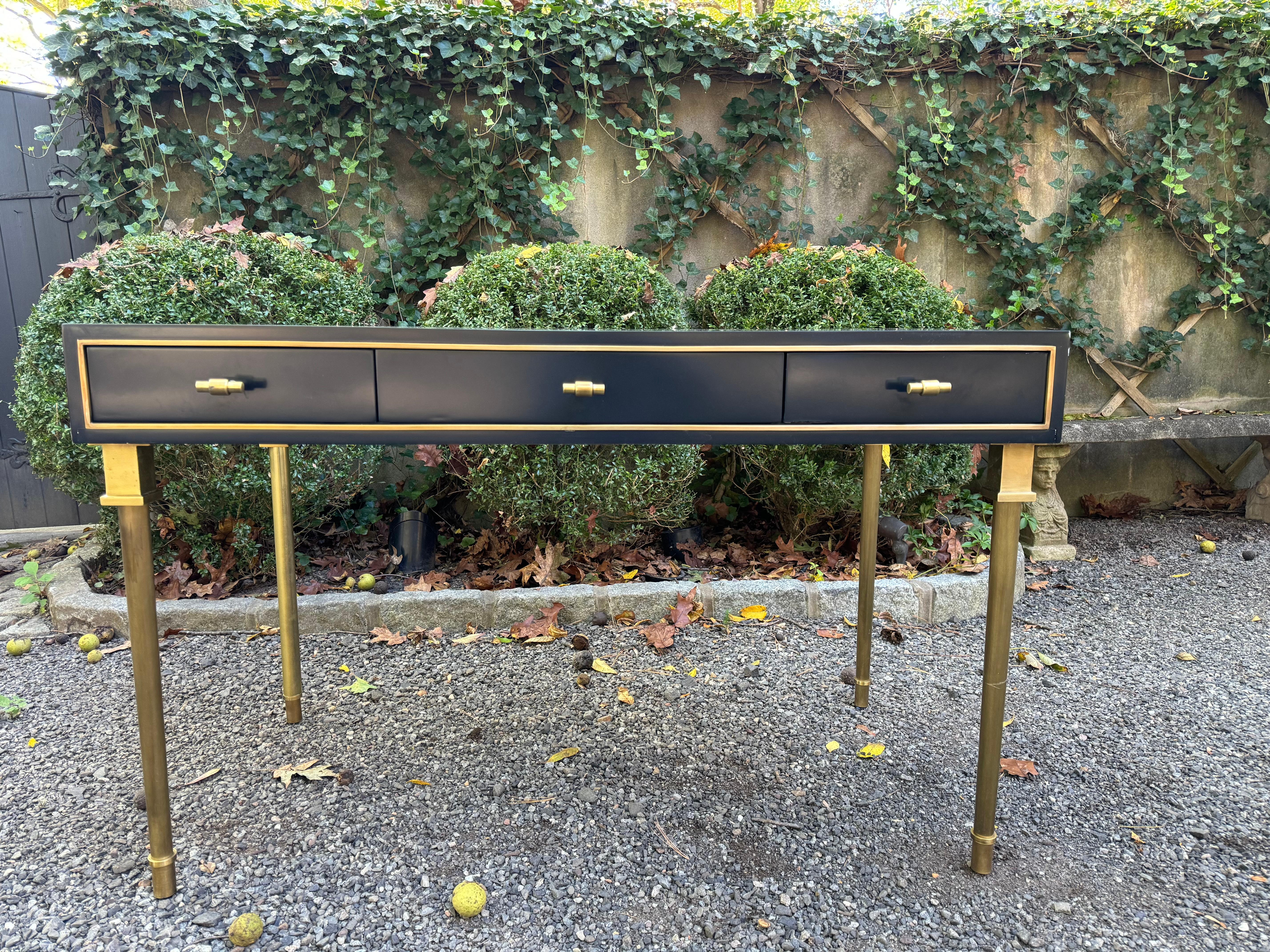 Stunning black laquered heavy beautifully constructed desk in the style of Maison Jansen having brass legs, hardware and trim that's a striking contrast and compliment to the black desk.  There are 3 drawers on one side, but the entire desk is