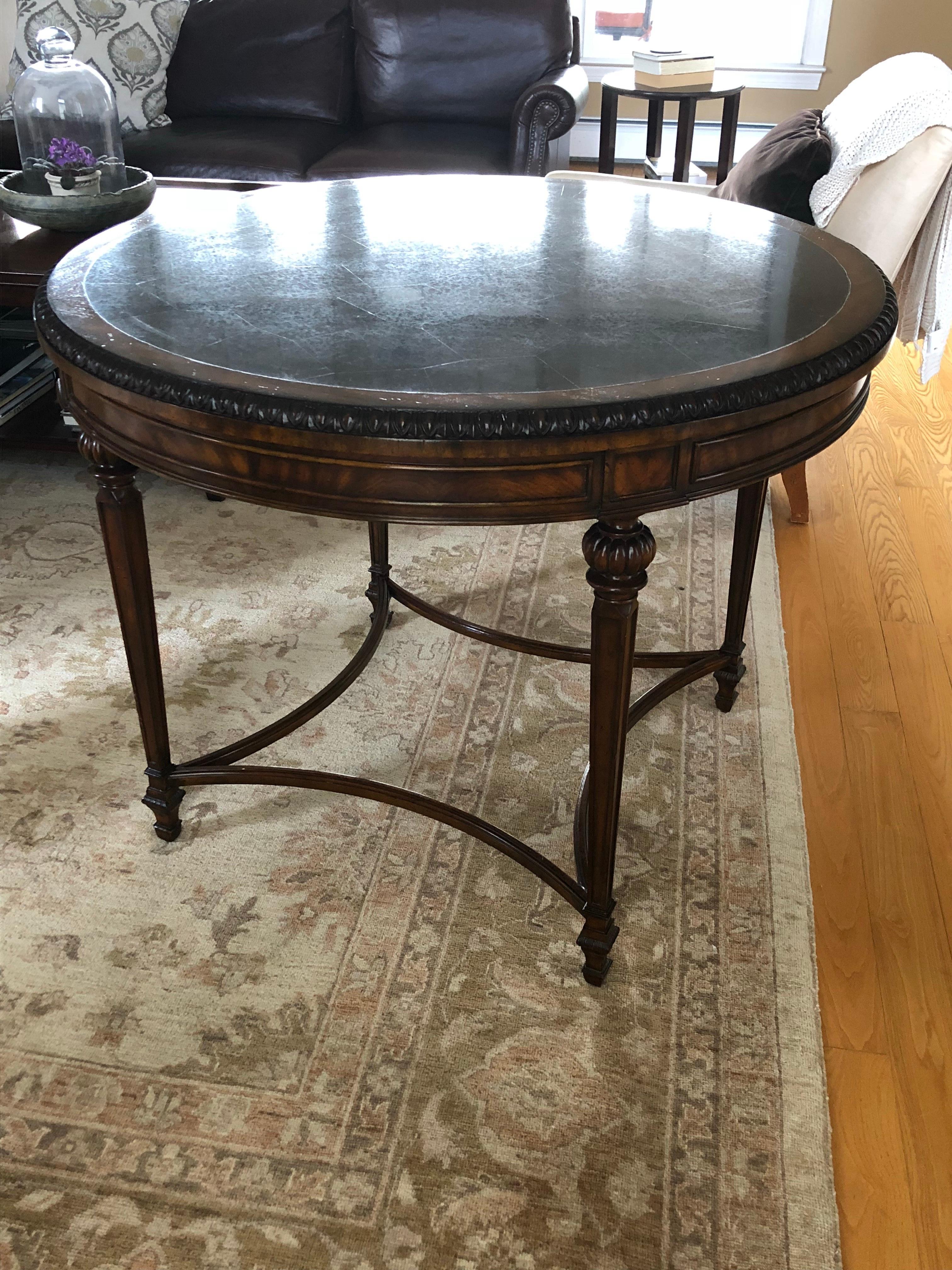 Beautiful round centre hall table or small dining table, having a black granite inlaid stone top with carved wood mahogany base.