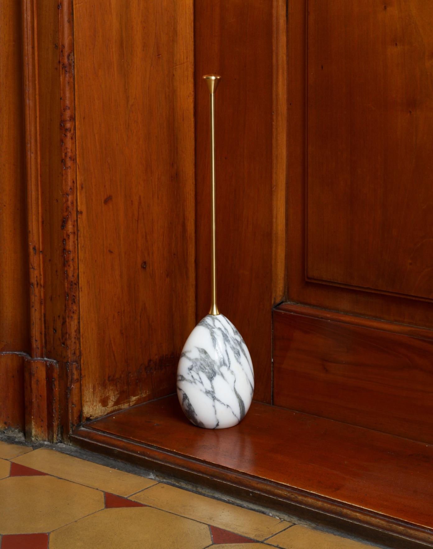 Mid-century Italian inspired doorstop. It pairs marble and brass to great effect. The sculpted handle provides a comfortable grip to securely place the doorstop where needed.
The handle is made of solid brass, oiled and threaded. It can also be