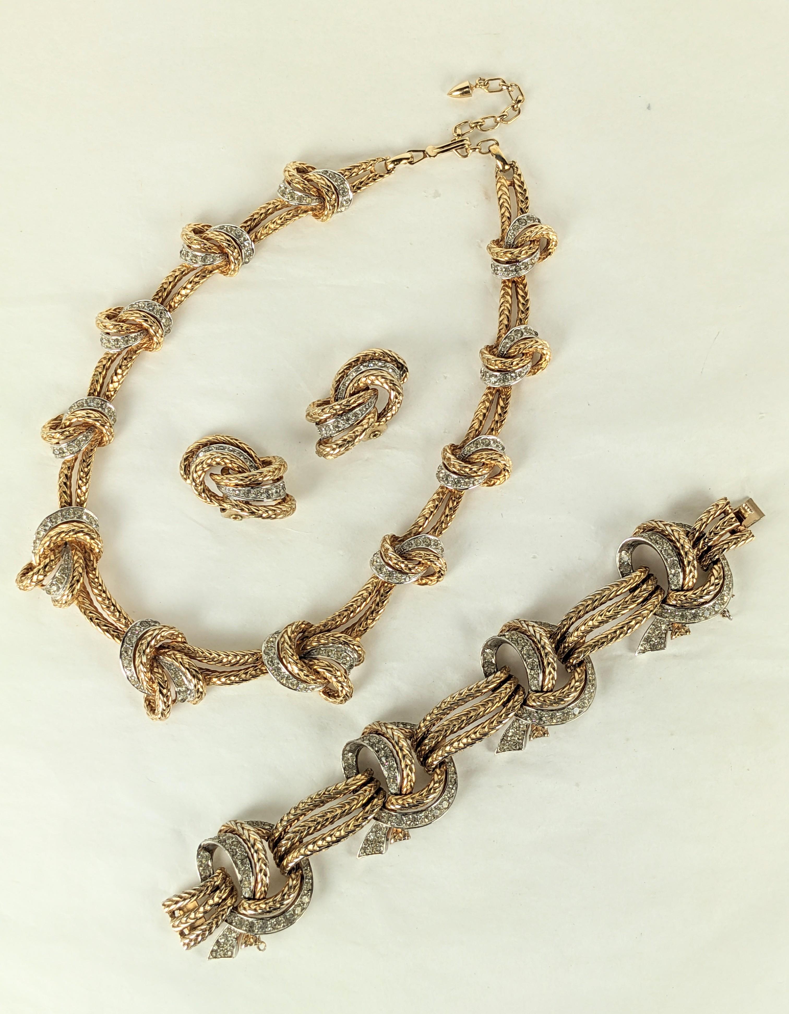 Elegant and Rare Marcel Boucher Gold and Pave Knot Suite from the 1950's. Graduated knot motifs in braided gilt metal with pave accents. Necklace, Bracelet and Earrings. 
Necklace Adjustable length. Fits 15