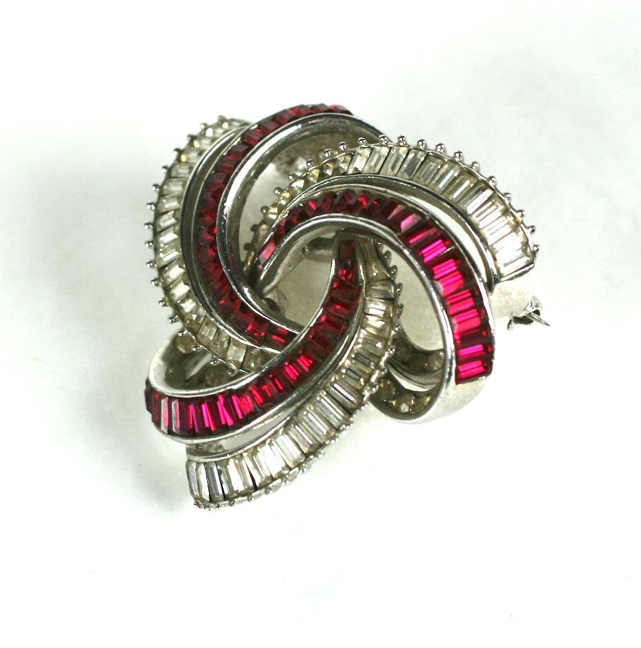 Elegant Boucher Knot Brooch representing an eternity knot in 3D with graduated ruby and crystal baguettes. Super high quality as to be expected from Marcel Boucher. Very dimensional and striking design.
1950's USA.  2