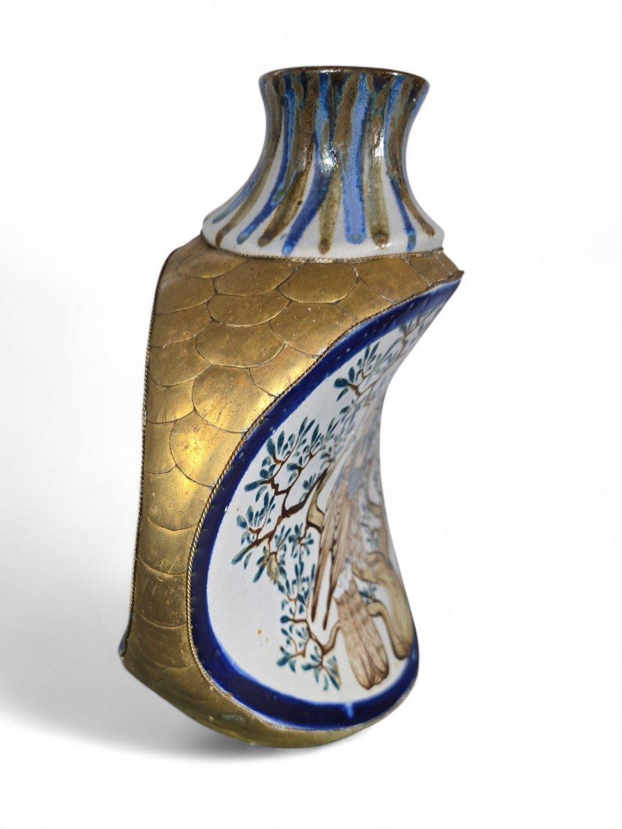 Superbe vase en porcelaine mexicaine, finement peint à la main, représentant un caméléon sur une face et un aigle majestueux sur l'autre, tous deux enchâssés dans un motif végétal stylisé.

Les côtés du vase sont ornés d'élégantes écailles en laiton