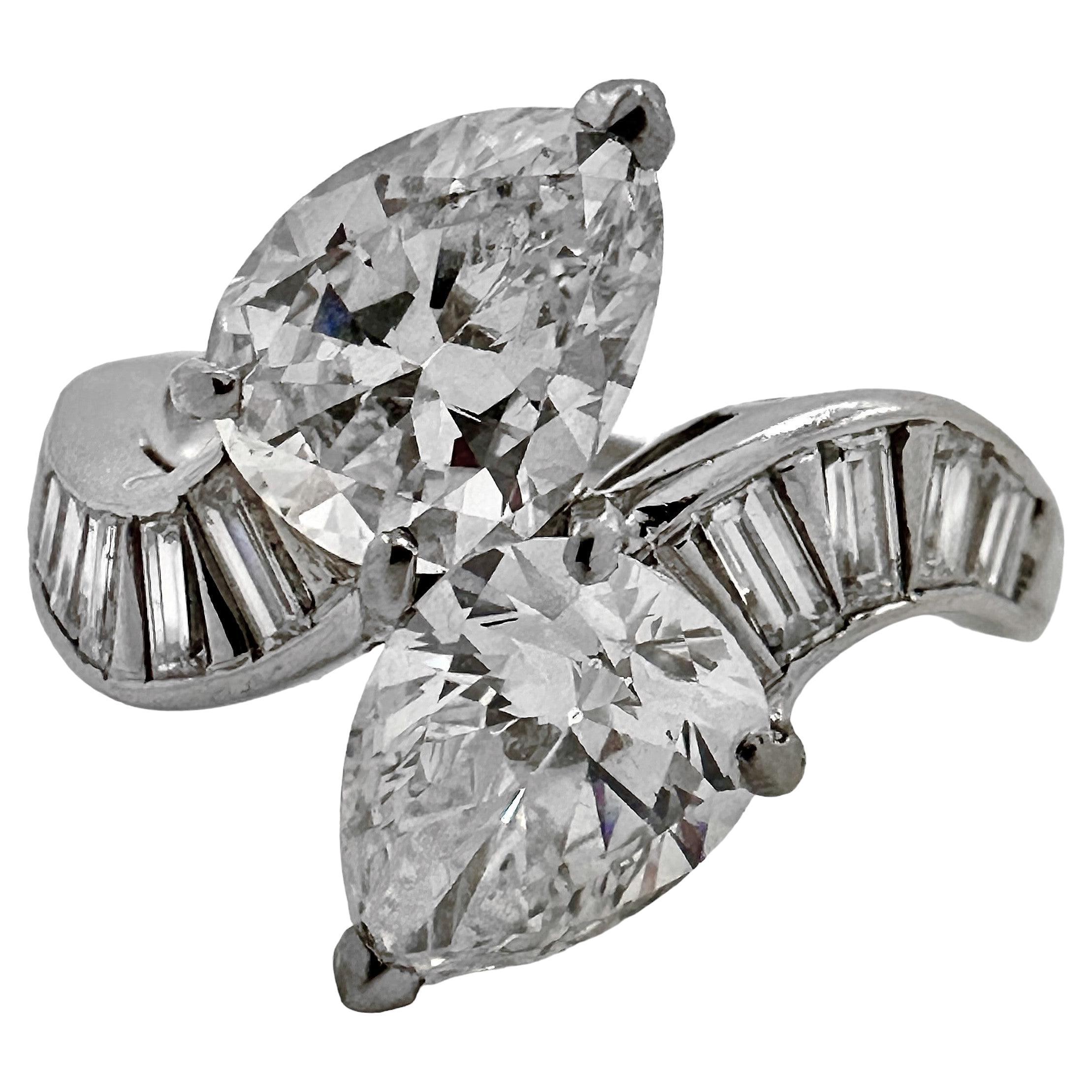 This traditional platinum bypass cocktail ring is set with two stunning pear shape, GIA certified diamonds* having an exact total weight of 2.66ct. Each stone is certified E color and VS1 clarity. Both shoulders are channel set with a total of ten