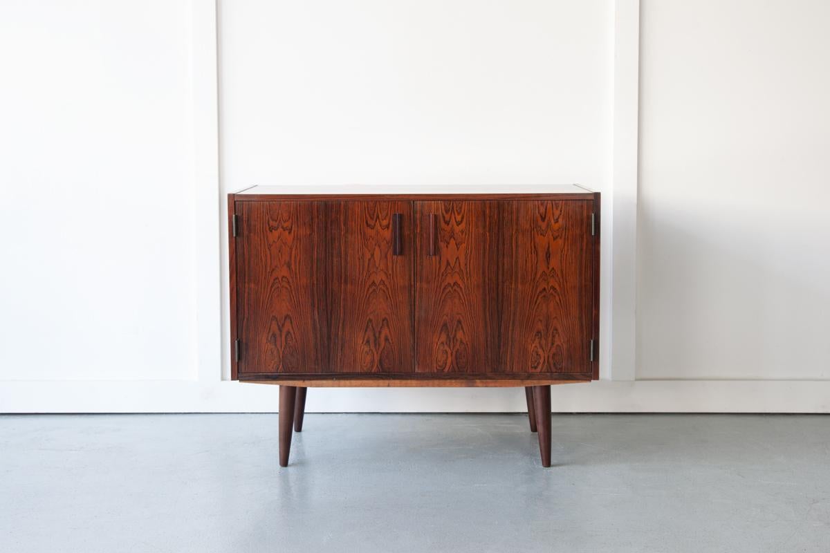 An elegant rosewood cabinet in a compact size, ideal for use as a drinks bar or television stand. The hinged doors open to reveal a single shelf inside. With splayed legs and prominent grain detailing, this is a stand out piece for any interior.
