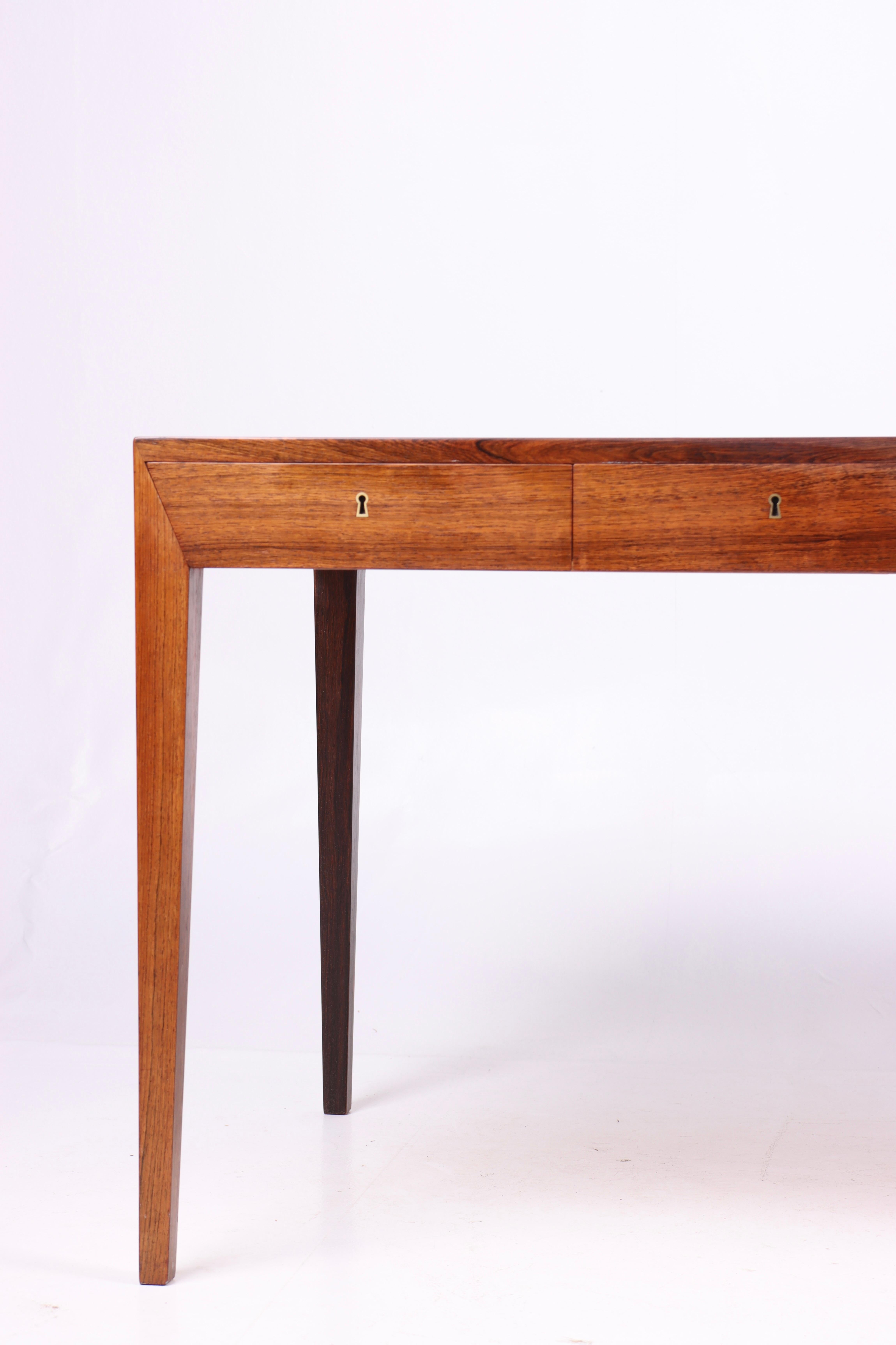 This desk is an iconic example of Danish midcentury design, created by the talented designer Severin Hansen and manufactured by the renowned Haslev Møbelfabrik in the 1950s. The desk is constructed from premium rosewood, characterized by its rich