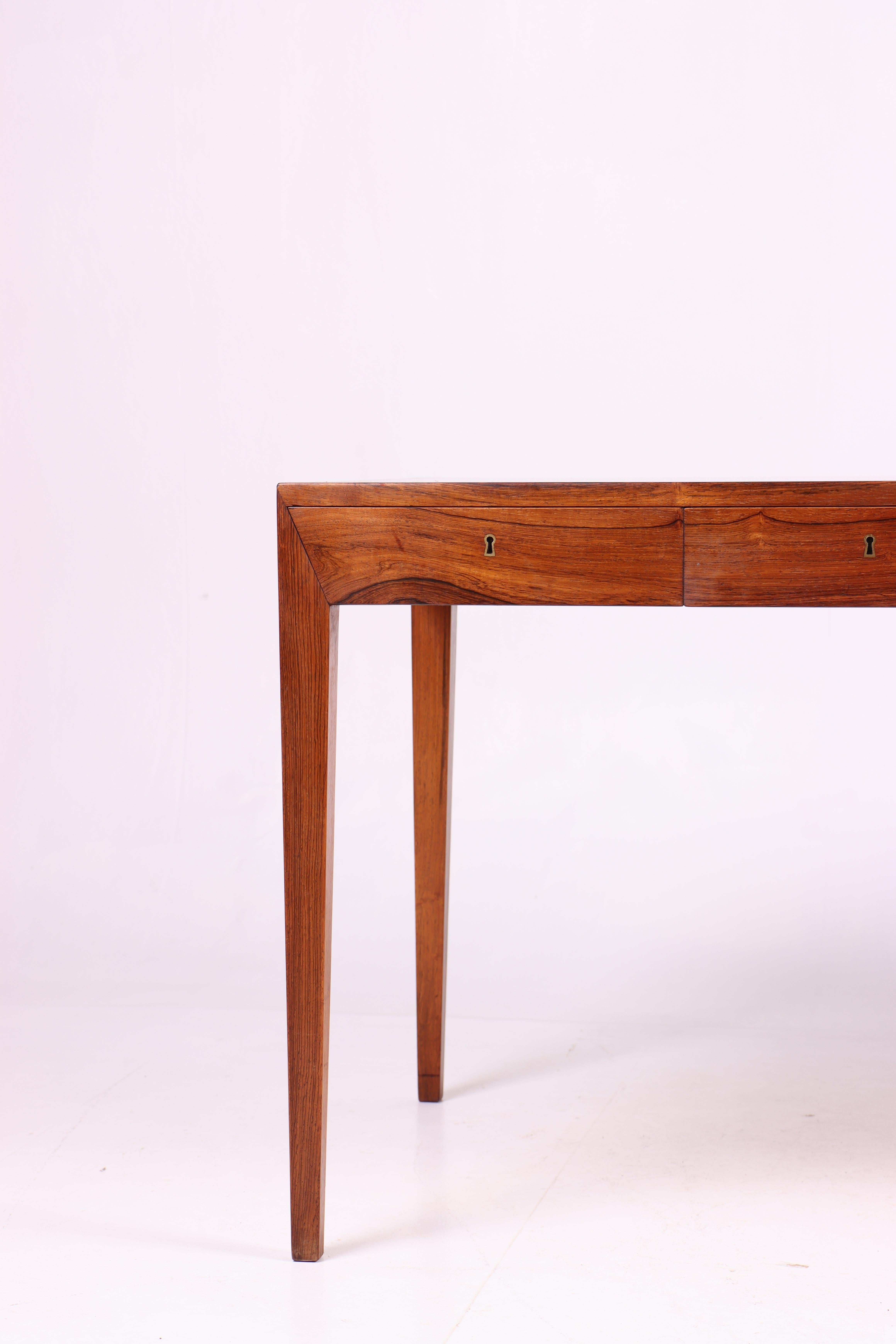 This desk is an iconic example of Danish midcentury design, created by the talented designer Severin Hansen and manufactured by the renowned Haslev Møbelfabrik in the 1950s. The desk is constructed from premium rosewood, characterized by its rich