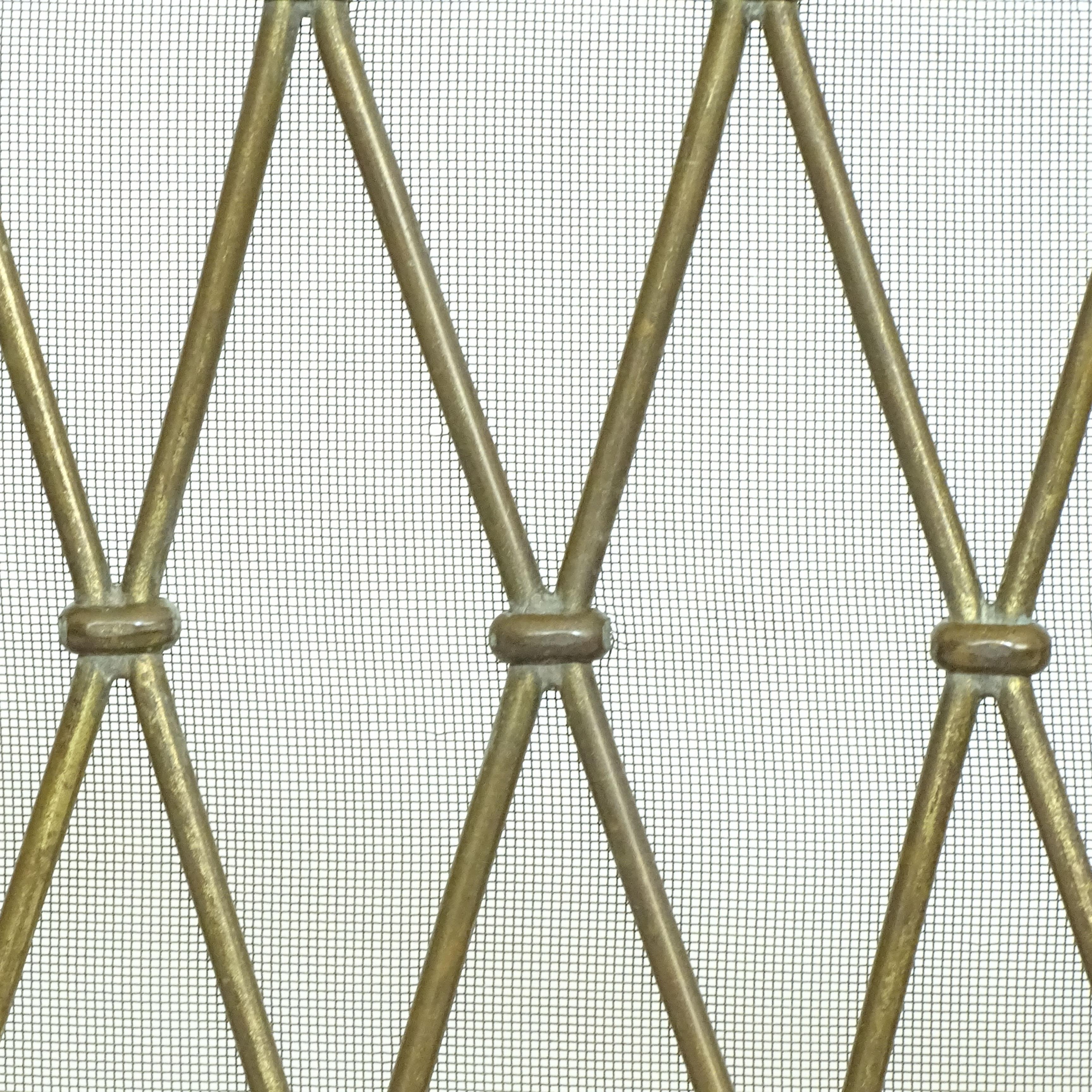 Grande parafuoco in ottone della metà del secolo scorso con design a reticolo di diamanti. La struttura è composta da sottili aste diagonali in ottone che si intersecano per formare un motivo a traliccio ripetuto, ogni giuntura è dettagliata con un