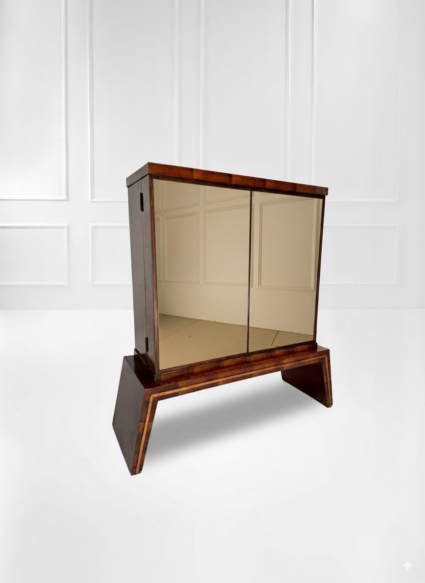 An elegant Italian dry bar, crafted from dark wood with a high-gloss finish. The bar features two mirrored doors that reflect the surrounding space, adding a touch of brightness and style. The structure rests on a wide, sturdy base with slightly