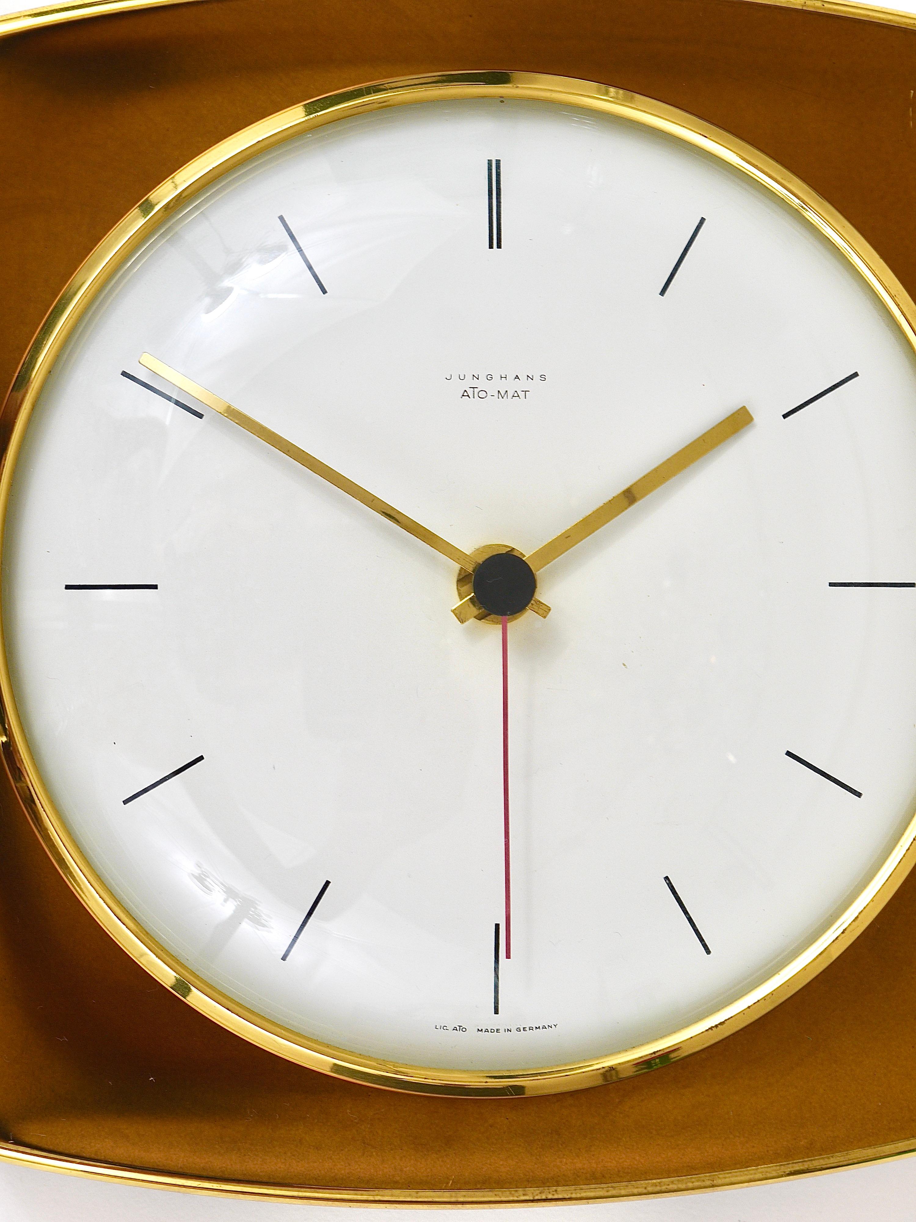 A beautiful square modernist brass wall clock in the style of Max Bill, executed in the 1950s by Junghans Germany. An elegant and decorative piece with a square golden metal housing, which ist partly polished. A nice straight clocks face and handles