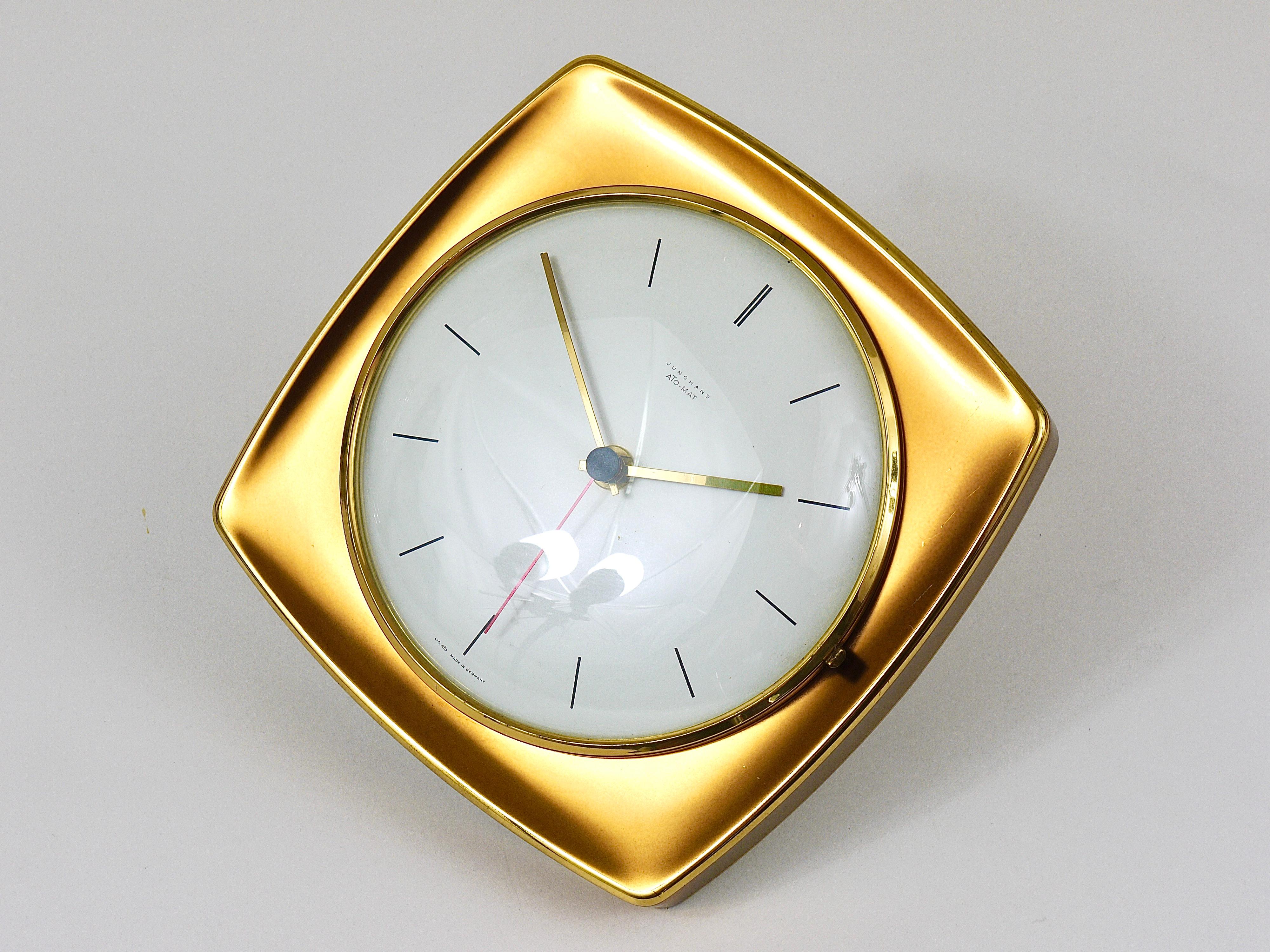 A beautiful square modernist brass wall clock in the style of Max Bill, executed in the 1950s by Junghans Germany. An elegant and decorative piece with a square golden metal housing, which ist partly polished. A nice straight clocks face and handles
