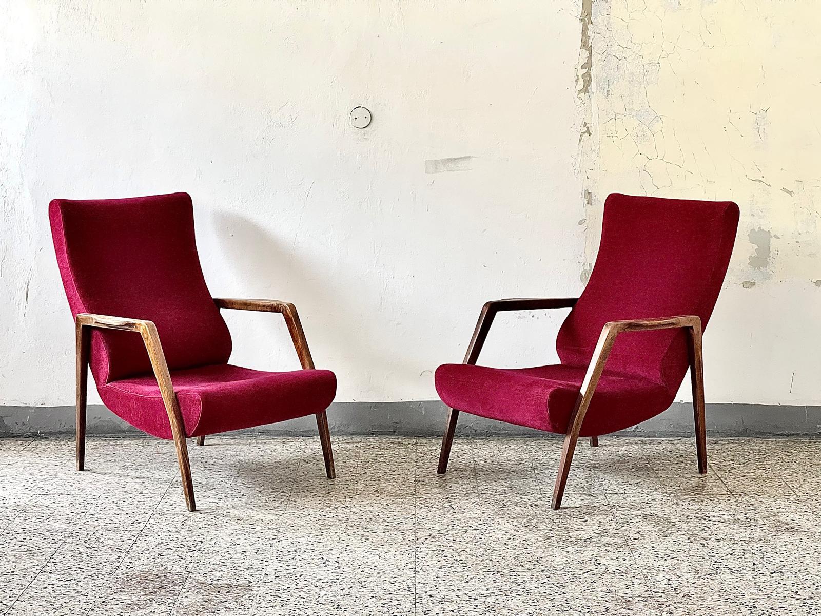Deux fauteuils italiens vintage, Mid-Century Modern 1960's, avec structure en bois et revêtement en tissu rouge raisin. Fabriqués en Italie, ils sont de belle facture, avec un bois uniformément lissé, une forme rationnelle et symétrique et une