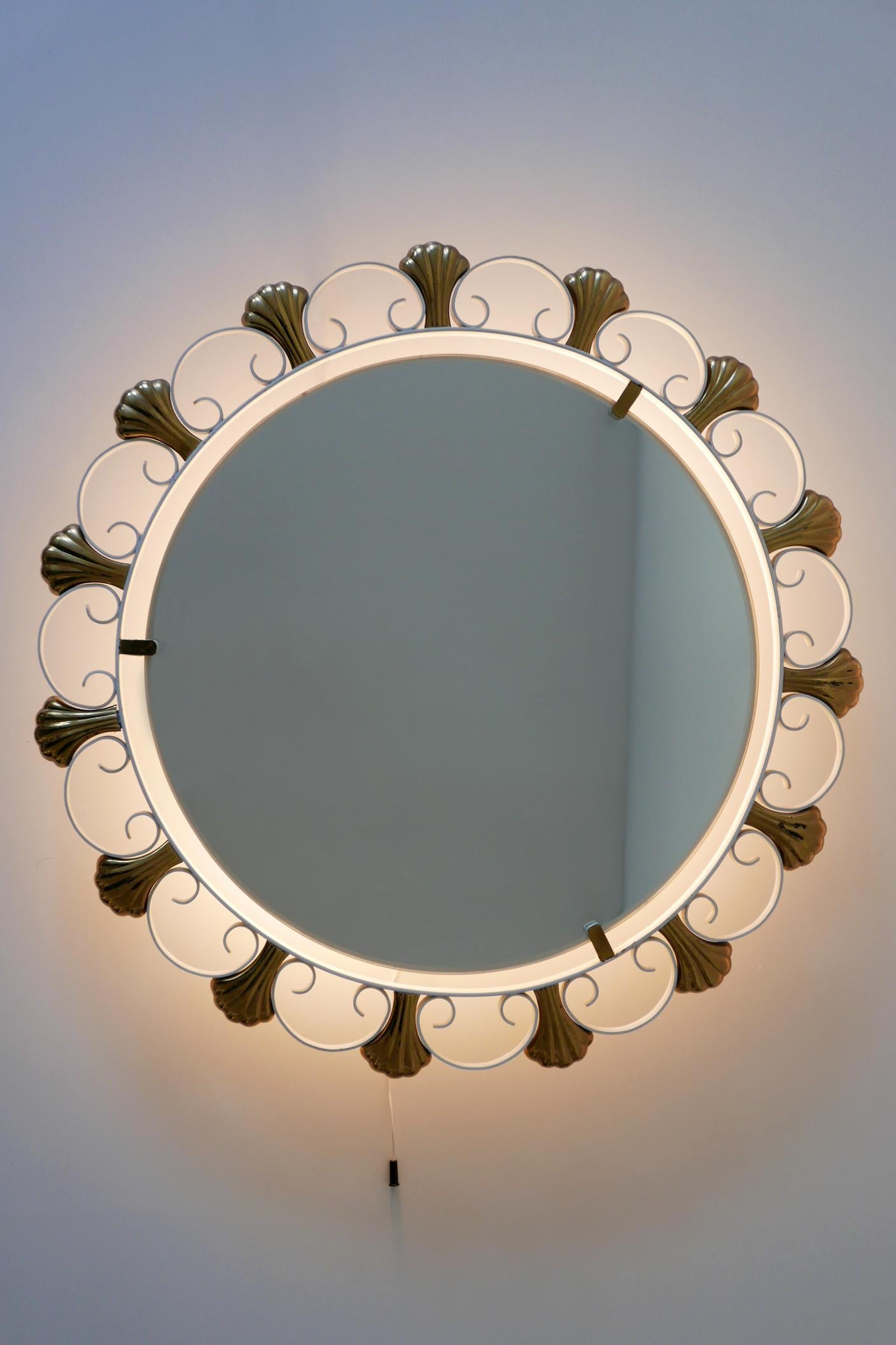 Eleganter Mid-Century Modern Wandspiegel mit Hintergrundbeleuchtung. Hergestellt von Hillebrand, 1950er Jahre, Deutschland. Herstellermarke auf dem Sockel.

Der aus weiß emailliertem Metall und Messing gefertigte Spiegel wird mit 4 x E14 / E12