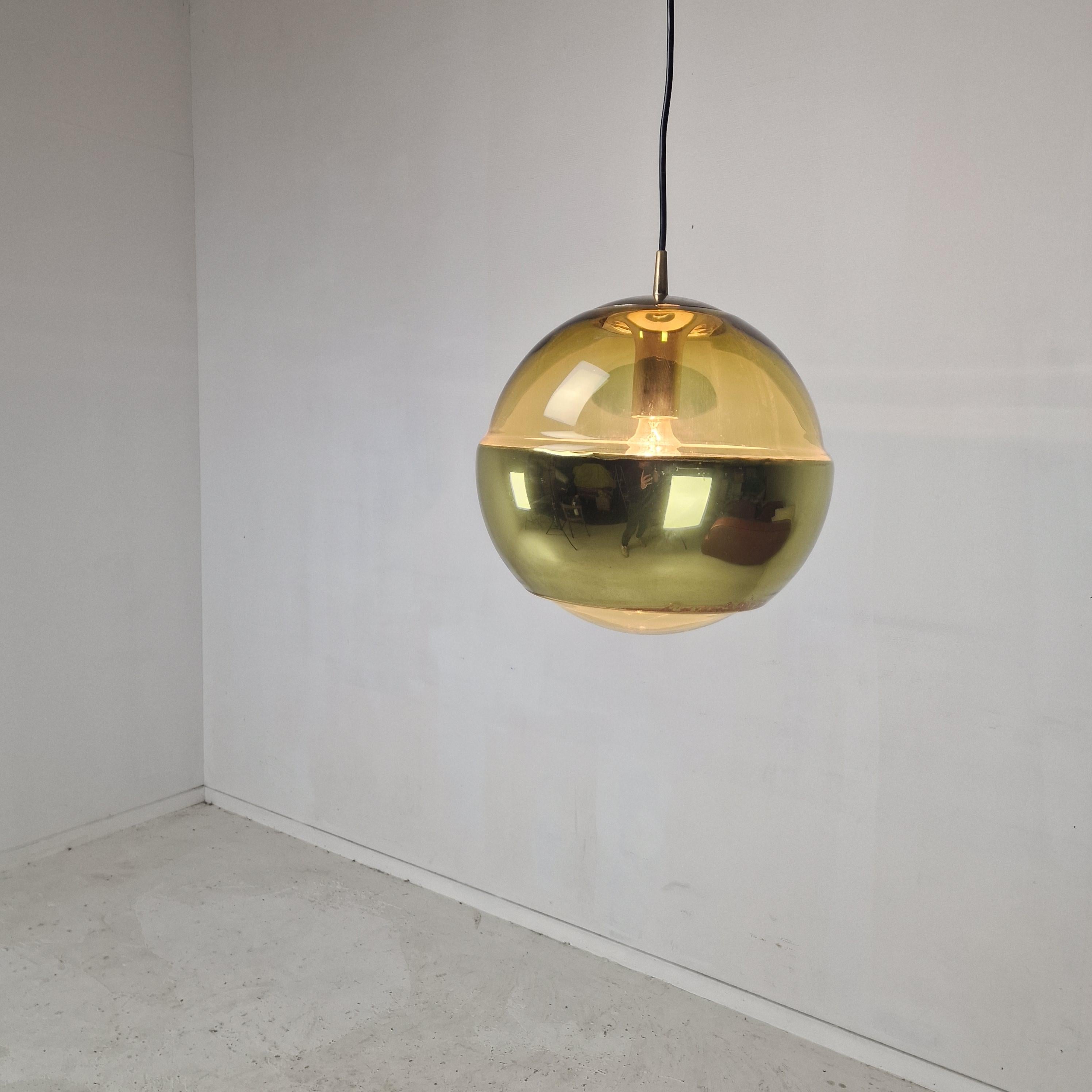 A striking single pendant light by renowned German manufacturer Peill & Putzler, crafted in the 1970s. The globe is made of molded, smoked glass and features a distinctive opaque, brass-colored coating on the lower half. The fixture is complemented