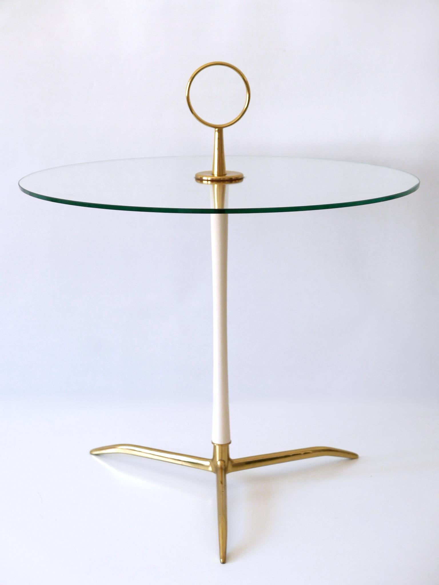 Extremely rare and elegant Mid-Century Modern tripod side table. Designed and manufactured by Vereinigte Werkstätten München, Germany, 1950s.

Executed in glass and brass; polished and partly enameled.

Condition:
Good original vintage condition.