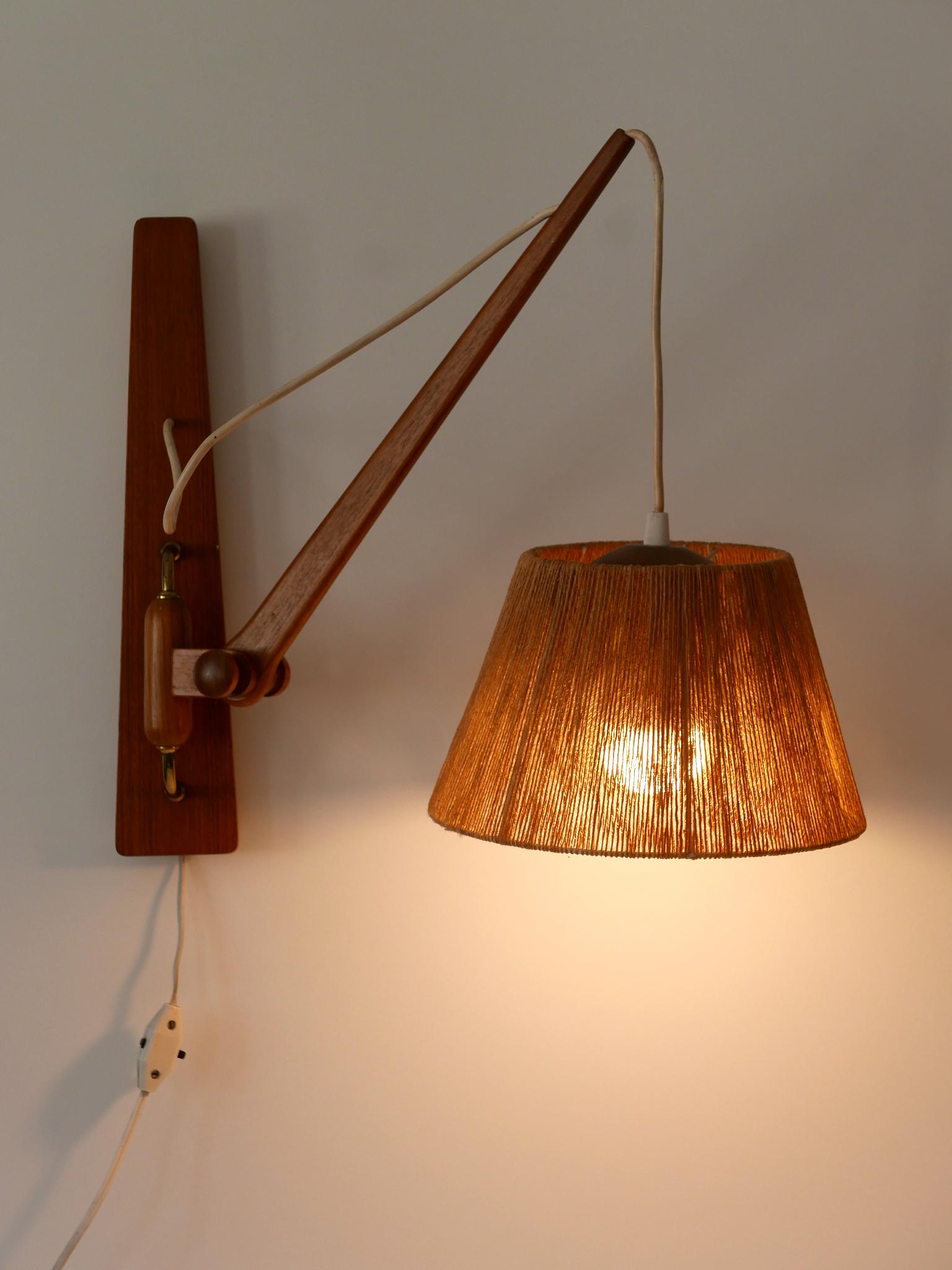 Raro y elegante aplique columpio moderno de mediados de siglo. Ajustable en vertical y horizontal. Diseñado y fabricado en Dinamarca, años 60.

Realizado en latón, madera de teca y sisal, el aplique viene con 1 portalámparas con rosca Edison E27 /