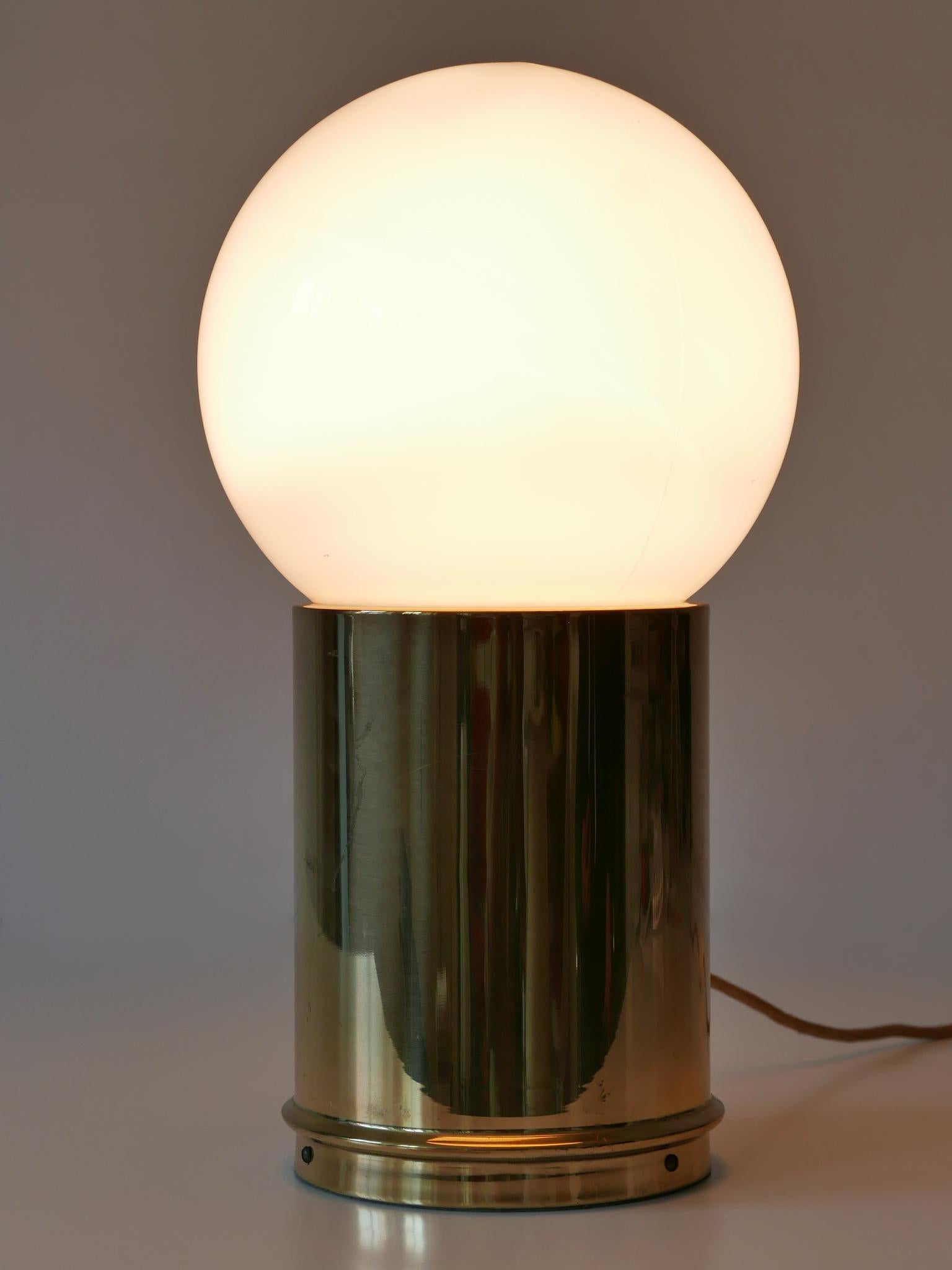 Rara ed elegante lampada da tavolo Mid-Century Modern. Progettato e prodotto da Vereinigte Werkstätten München, Germania, anni '60.

Realizzata in ottone e vetro, la lampada è dotata di 1 attacco per lampadina a vite E27 / E26 di Edison, è dotata di