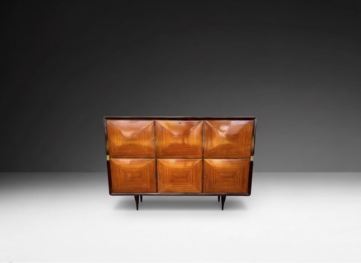 Ce buffet des années 1950 présente un élégant design du milieu du siècle. Il est réalisé en bois avec une finition brillante qui met en valeur les veines, disposées en panneaux géométriques en forme de losange sur les façades des portes. Il comporte
