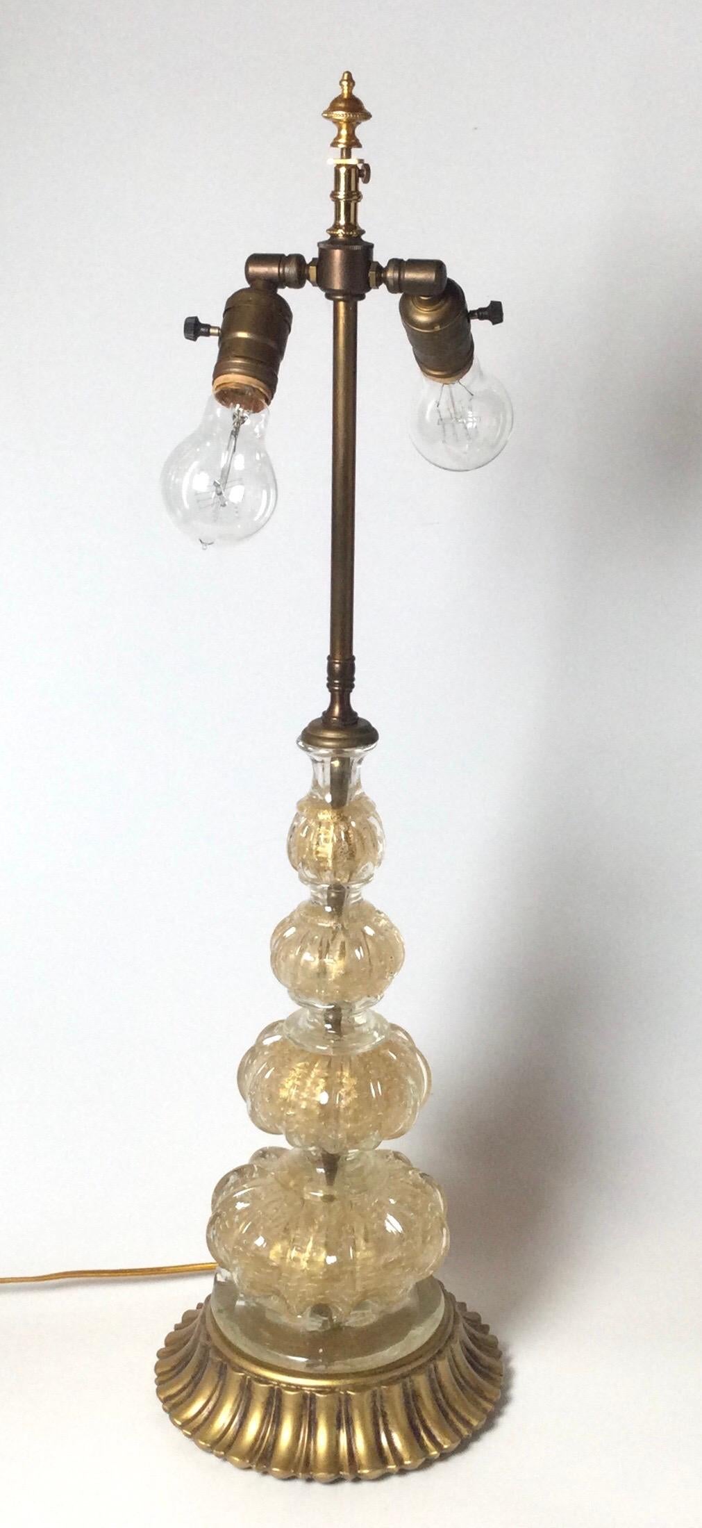 Very Chic Italian Venetian glass lamp with giltwood base. The center column with variegated sizes of orbs in a gold fleck infused hand blown Venetian glass. The base is a scalloped gilt wood, with two sockets for extra light. The shade is for
