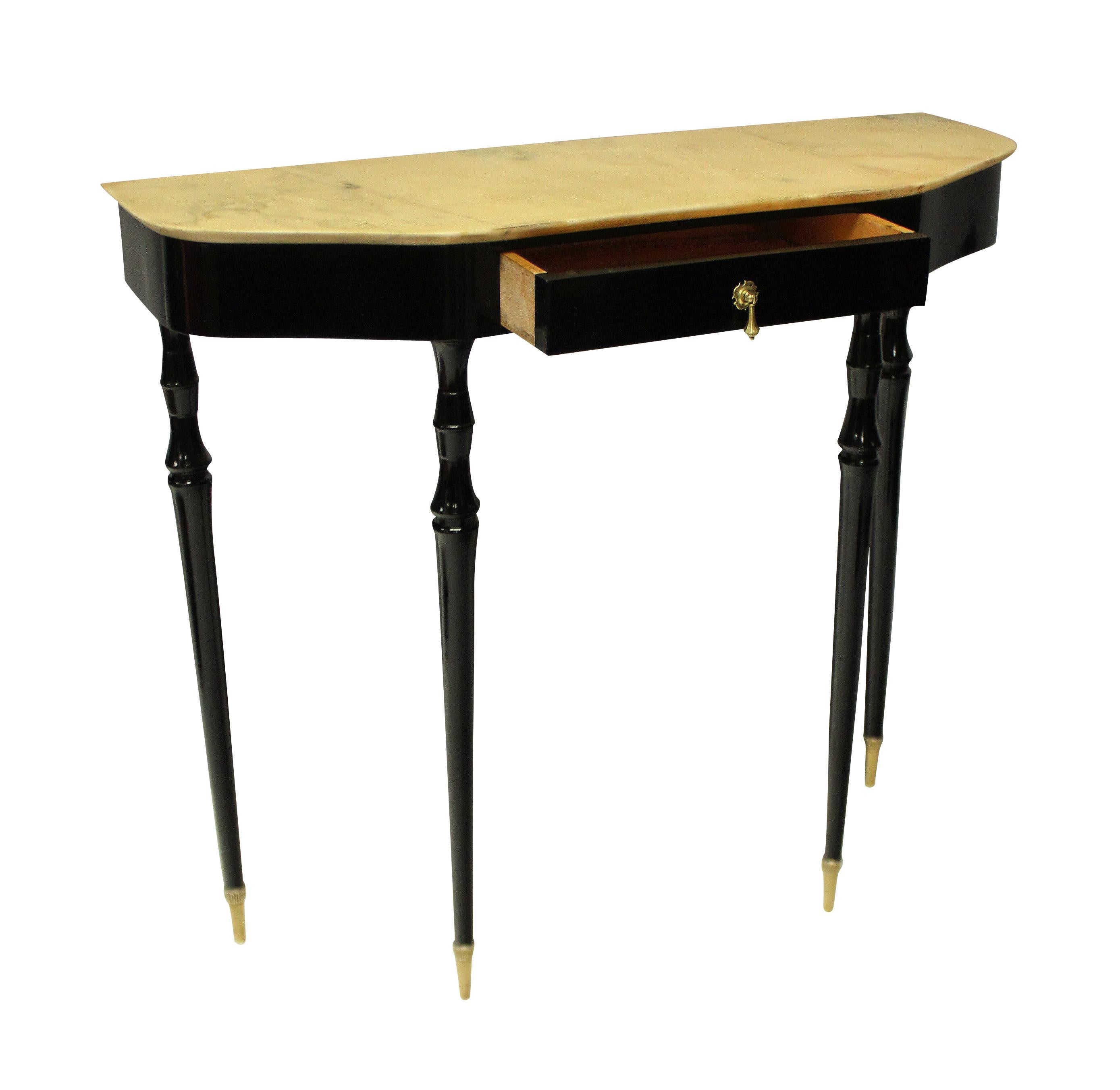 An elegant Italian mid century console table, ebonised with tapering legs, a frieze with drawer, brass handle and sabot and a cream marble top.