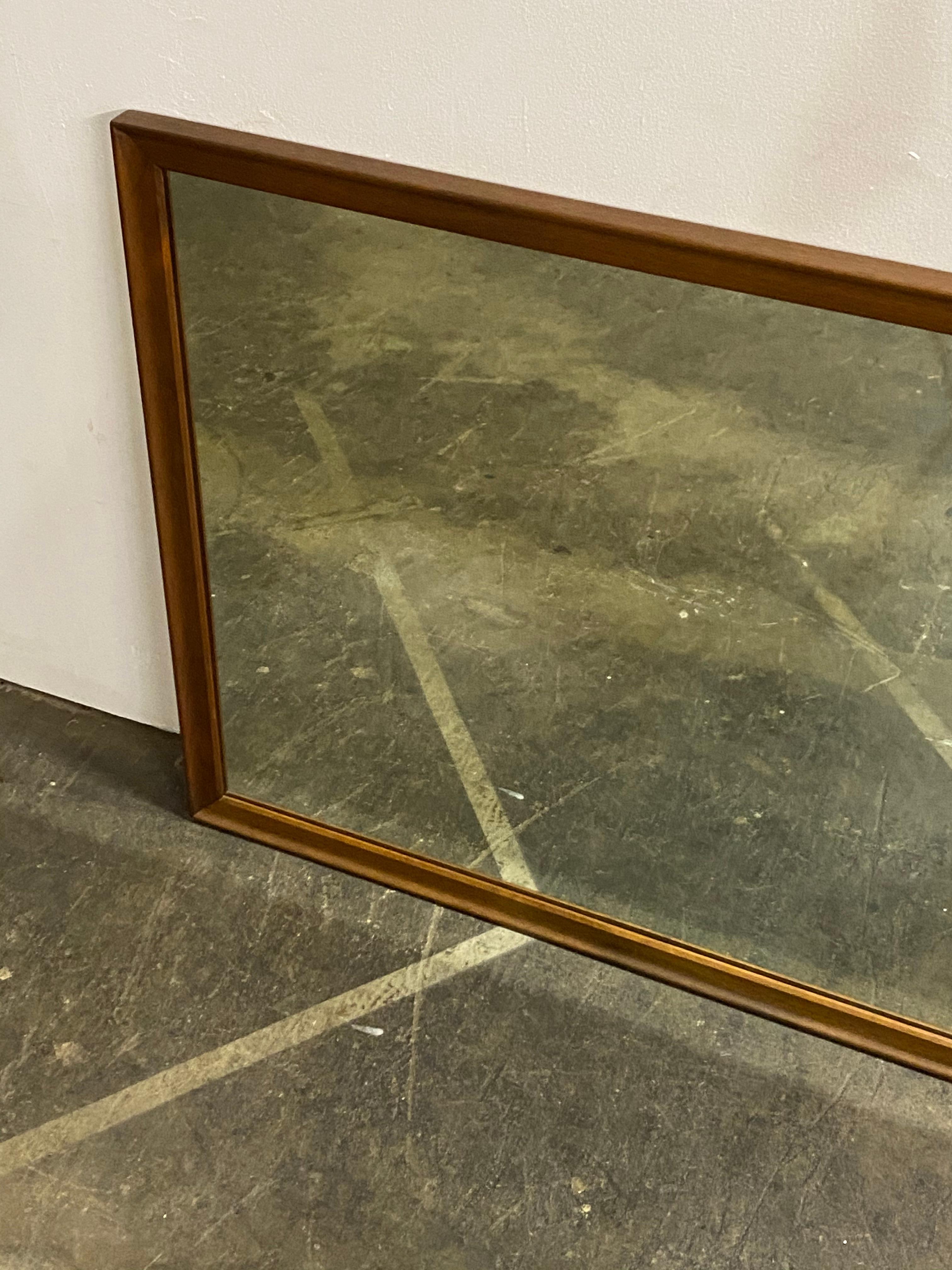 Elegant walnut rectangular mirror by Drexel. Designed by Kipp Stewart. Even warm walnut tones outline the large surface mirror. Substantial yet understated. Solid and sturdy and ready to hang.