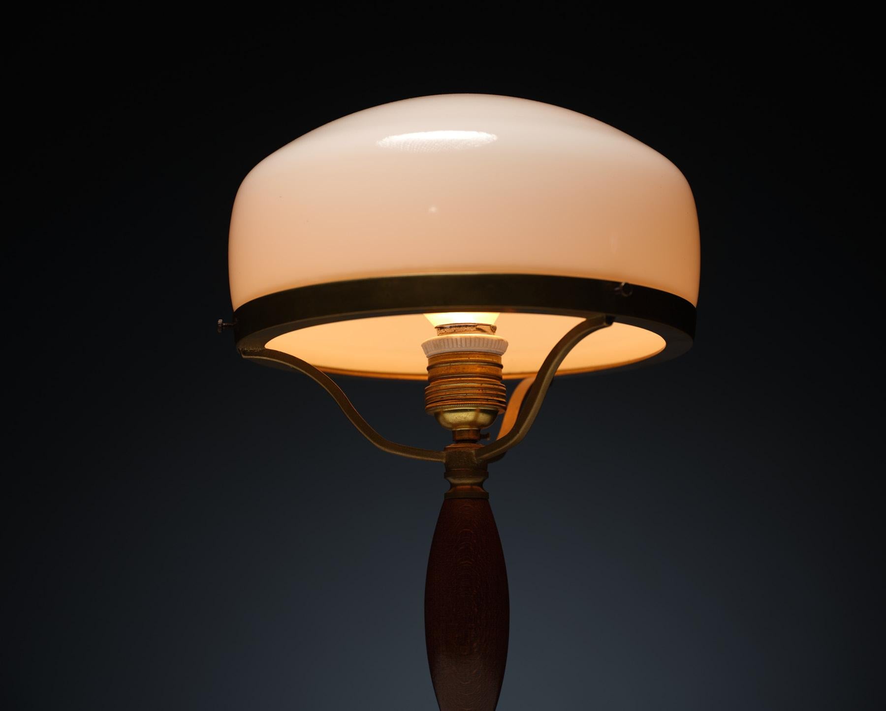 Introducing our exquisite vintage table lamp that effortlessly embodies midcentury charm and timeless elegance. Crafted from lustrous brass with its original patina, this lamp exudes a sense of precious history. The rich, dark-stained beechwood base