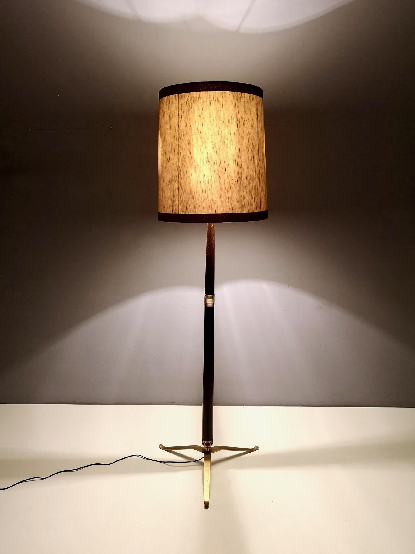 This floor lamp is made in wood, brass and varnished metal and has a fabric and varnished metal lampshade. 
Its wiring is new and features three lights: a single one and a pair and they can be switched on separately or at the same time. 
It might