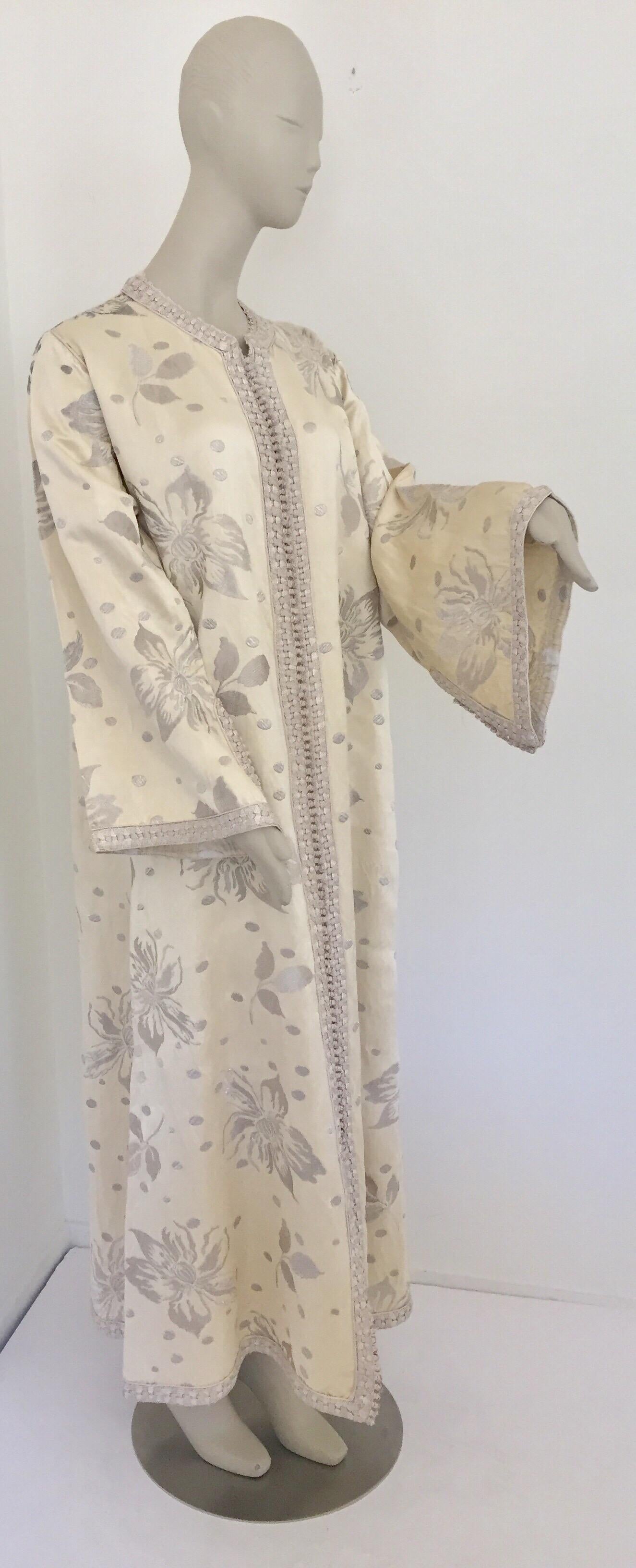 Atemberaubender und eleganter marokkanischer Kaftan mit silbernem, metallischem maurischem Blumen-Dupioni-Seidenbrokat.
Aufwendig bestickt auf einer wunderschönen gewebten Dupionseide, sind die Blumen mit metallischem, silbernem Seidenfaden