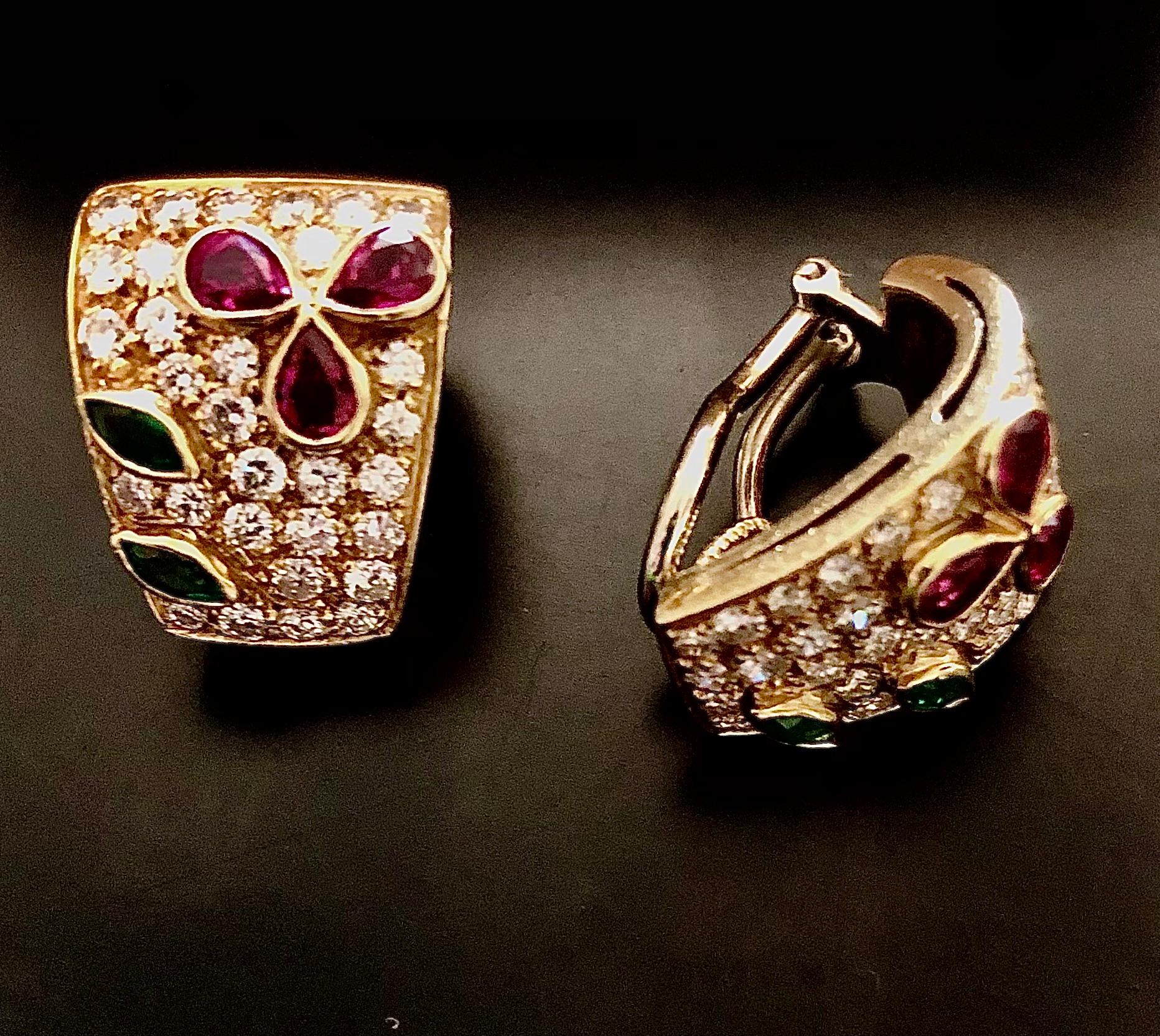 Jolie paire de clips d'oreilles en or jaune 18 carats, élégants et contenant plusieurs pierres précieuses. La surface est pavée de diamants blancs étincelants incrustés d'un décor floral abstrait composé d'émeraudes, de tourmalines et de rubis