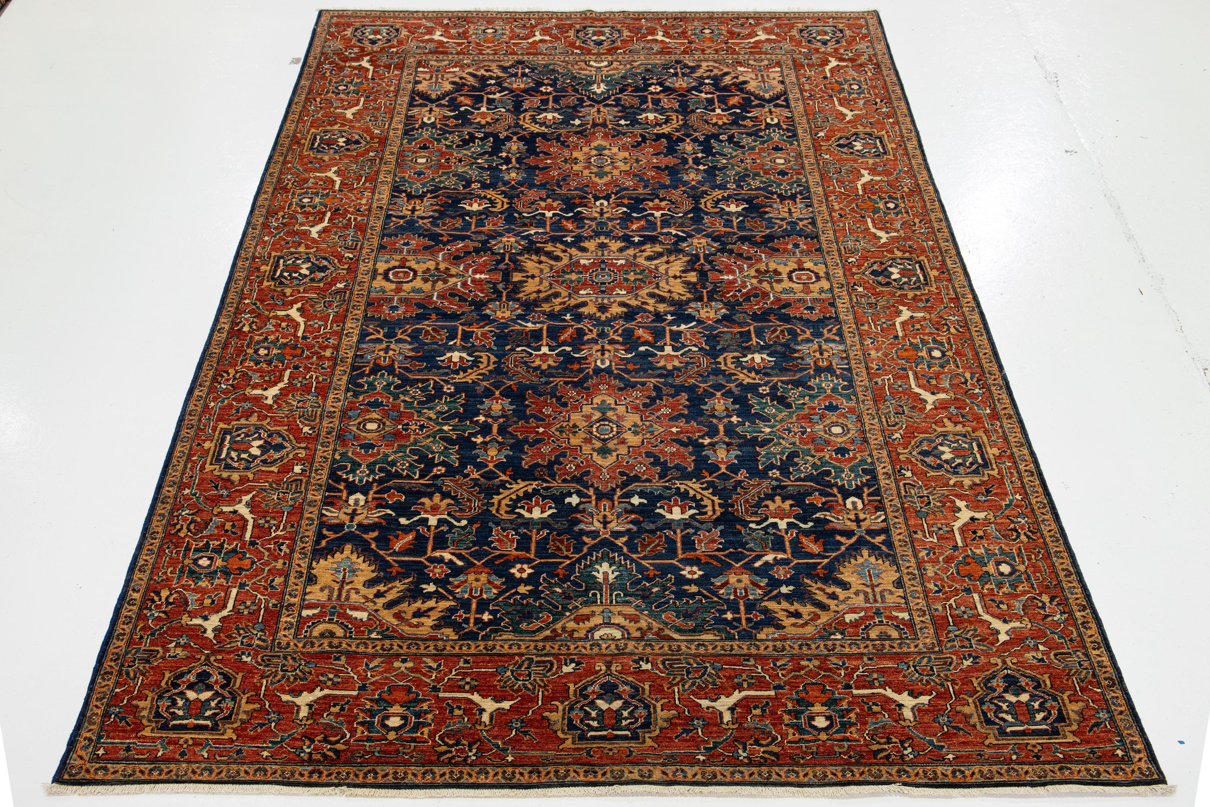 This refined wool rug combines a timeless navy blue backdrop with a contemporary Serapi-inspired design. The piece showcases a red-designed frame and a breathtaking all-over floral pattern with exquisite multicolor accents. It adds a touch of