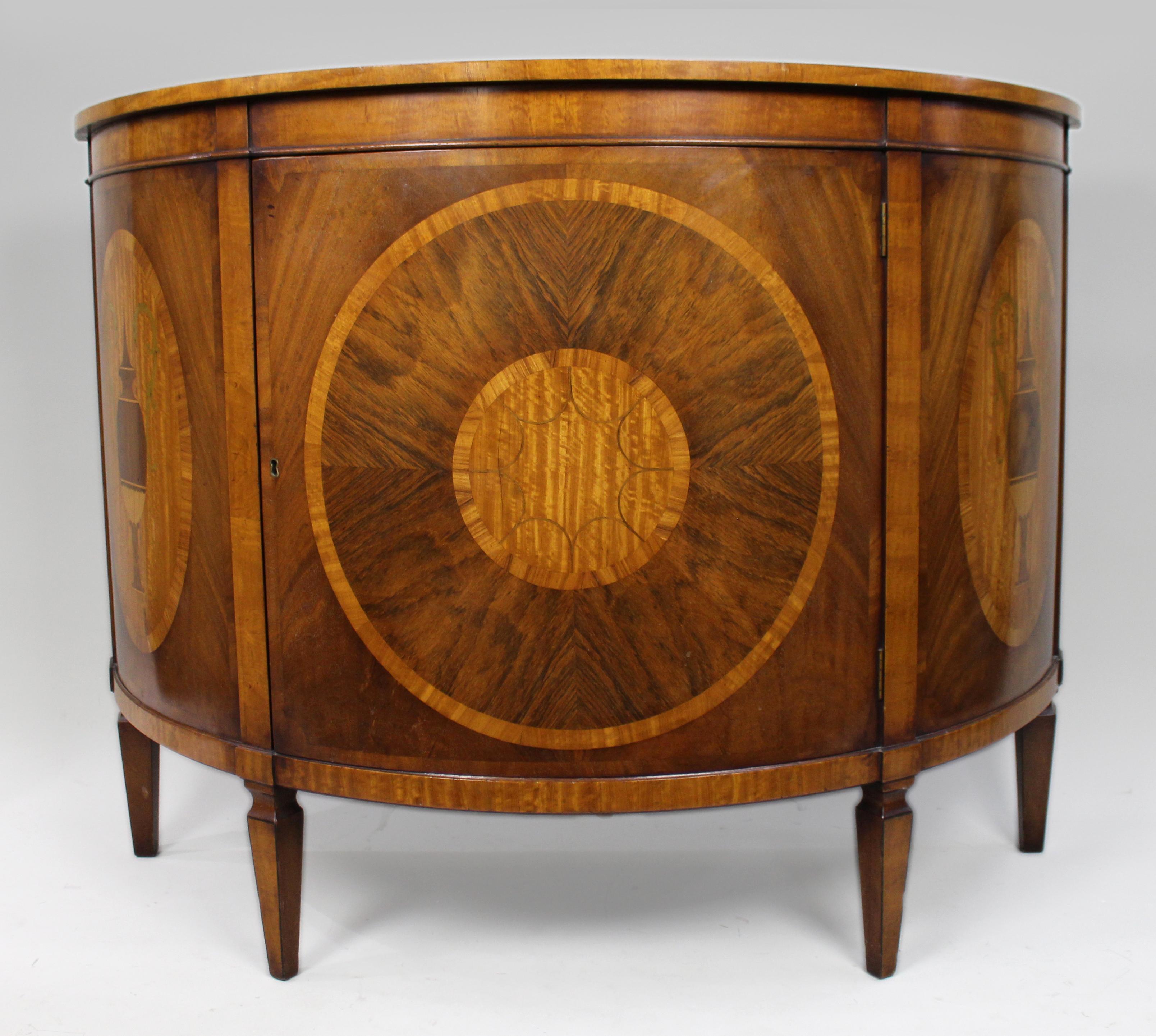 Elegant Neoclassical Style Inlaid Demilune Cabinet, Late 20th Century


A beautifully crafted demilune side cabinet in the refined neoclassical taste, veneered with a harmonious palette of figured woods and decorative inlays. The bow-fronted form is