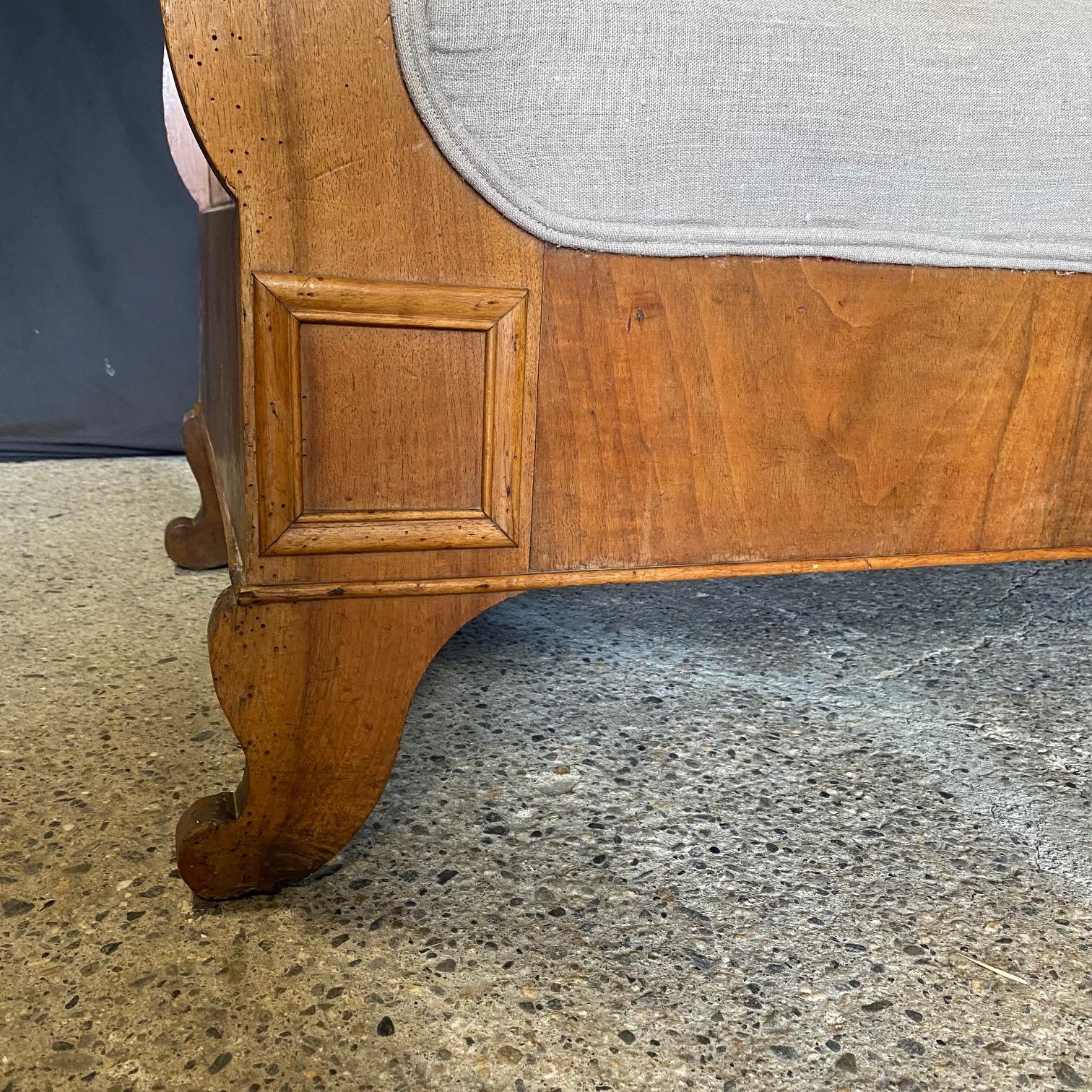 Precioso y raro sofá antiguo Biedermeier tallado con chapas de madera de nogal de primera calidad. Presenta maravillosos motivos redondeados en el brazo y los pies suavemente curvados, y un maravilloso tejido neutro que realza las líneas del sofá.