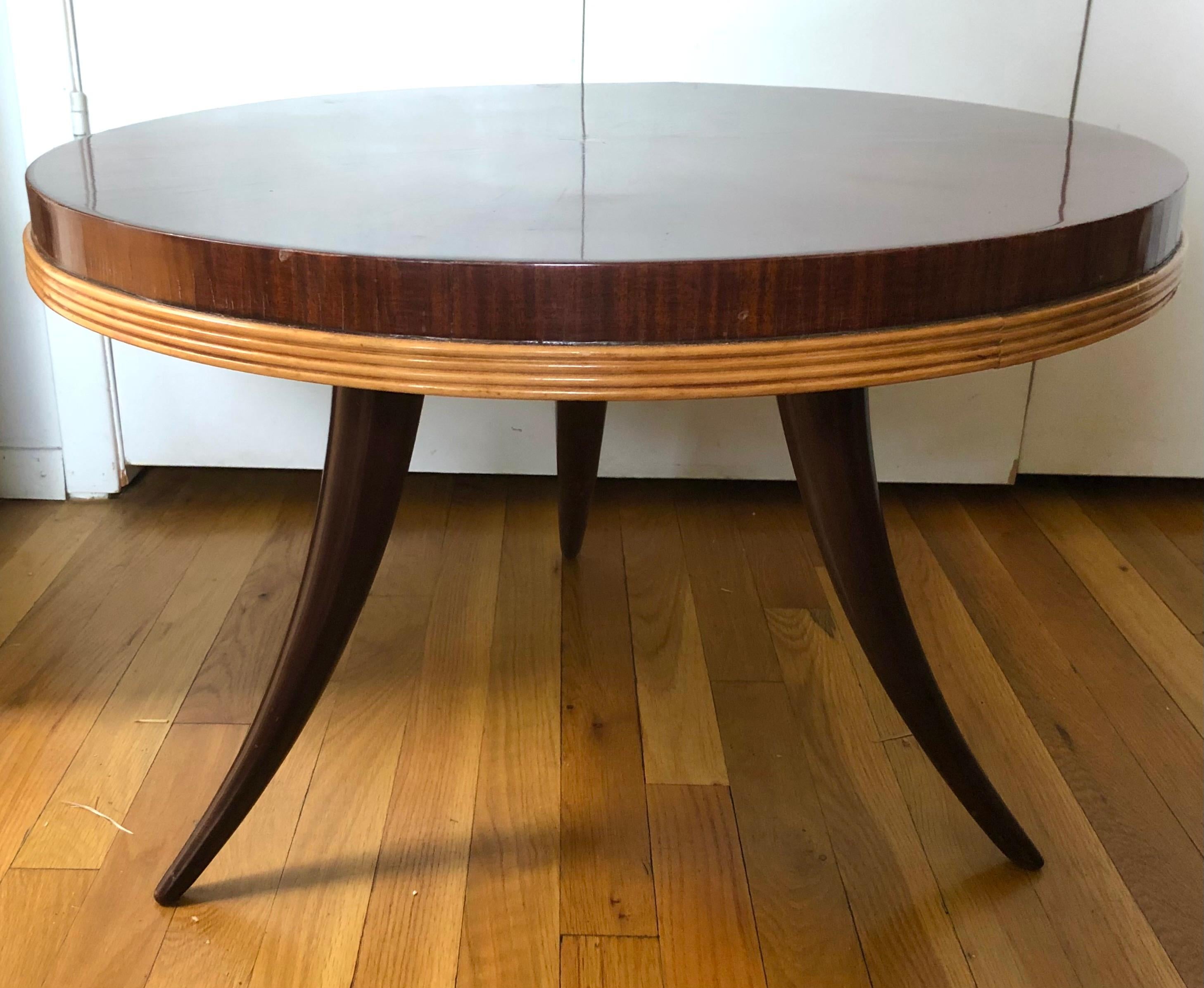 c. 1950, mahogany, ash, fruitwood, the round top clad in starburst pattern mahogany veneer with central brass star inlay, over three round tapered and sharply sabered legs, with channeled ash banding around frieze. 

Unlabeled but beautiful quality