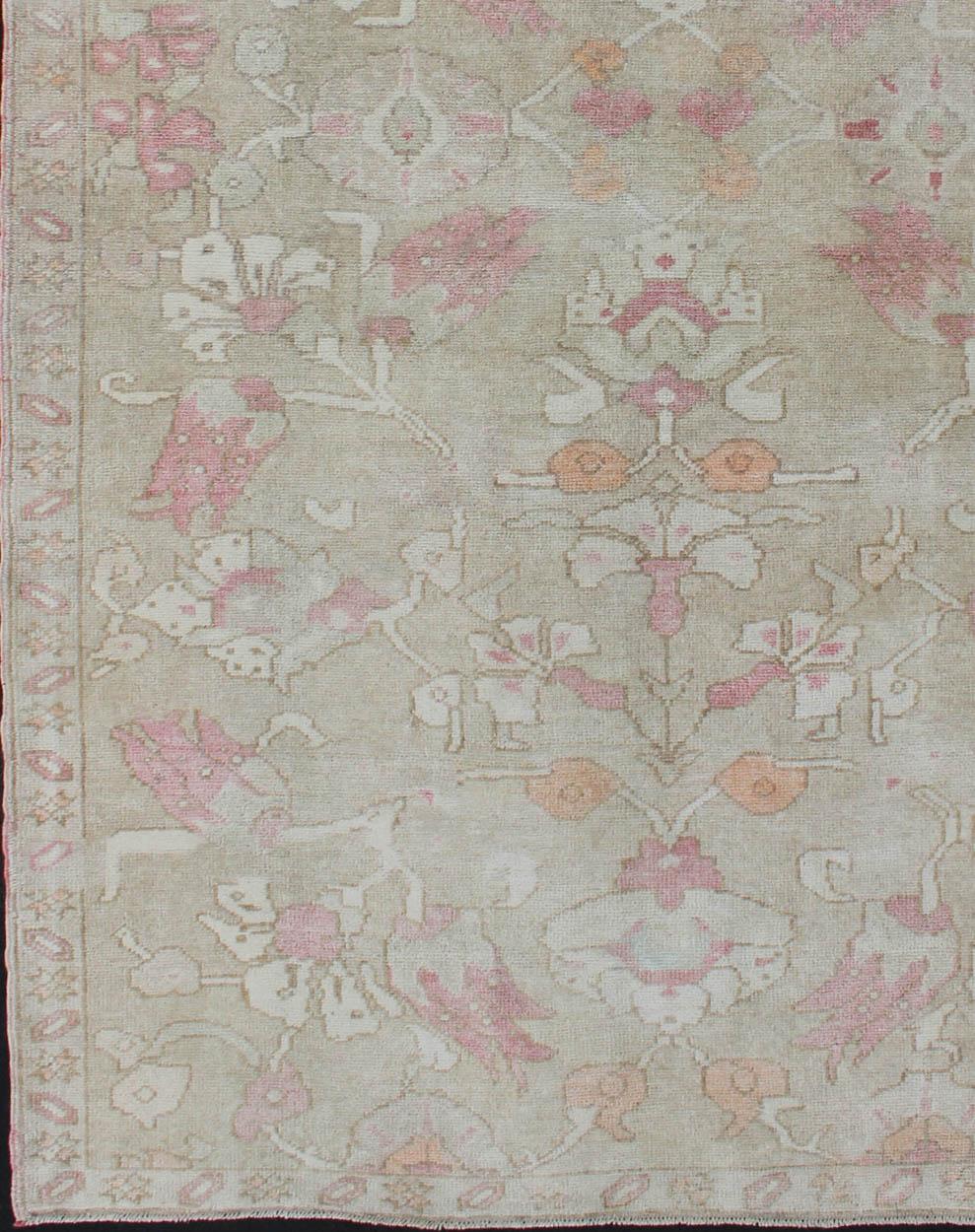 Pink, apricot, and ivory vintage rug with flower pattern, rug en-112809, country of origin / type: Turkey / Oushak, circa 1950

This vintage Tulu carpet features a beautiful flower pattern, set atop a greenish-gray background and rendered in tones