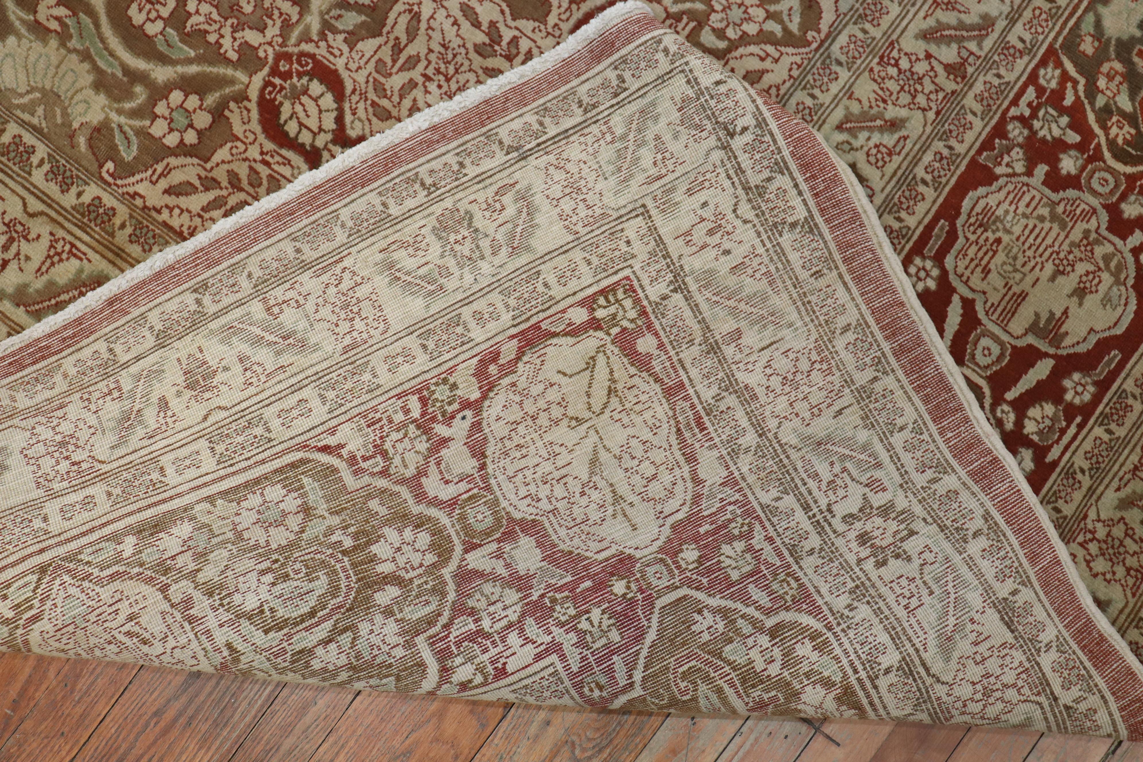 An oversize Antique Persian Tabriz rug woven early 20th century with cinnamon colored ground and soft brown medallion. The inscription pictured reads that the rug was woven in the 