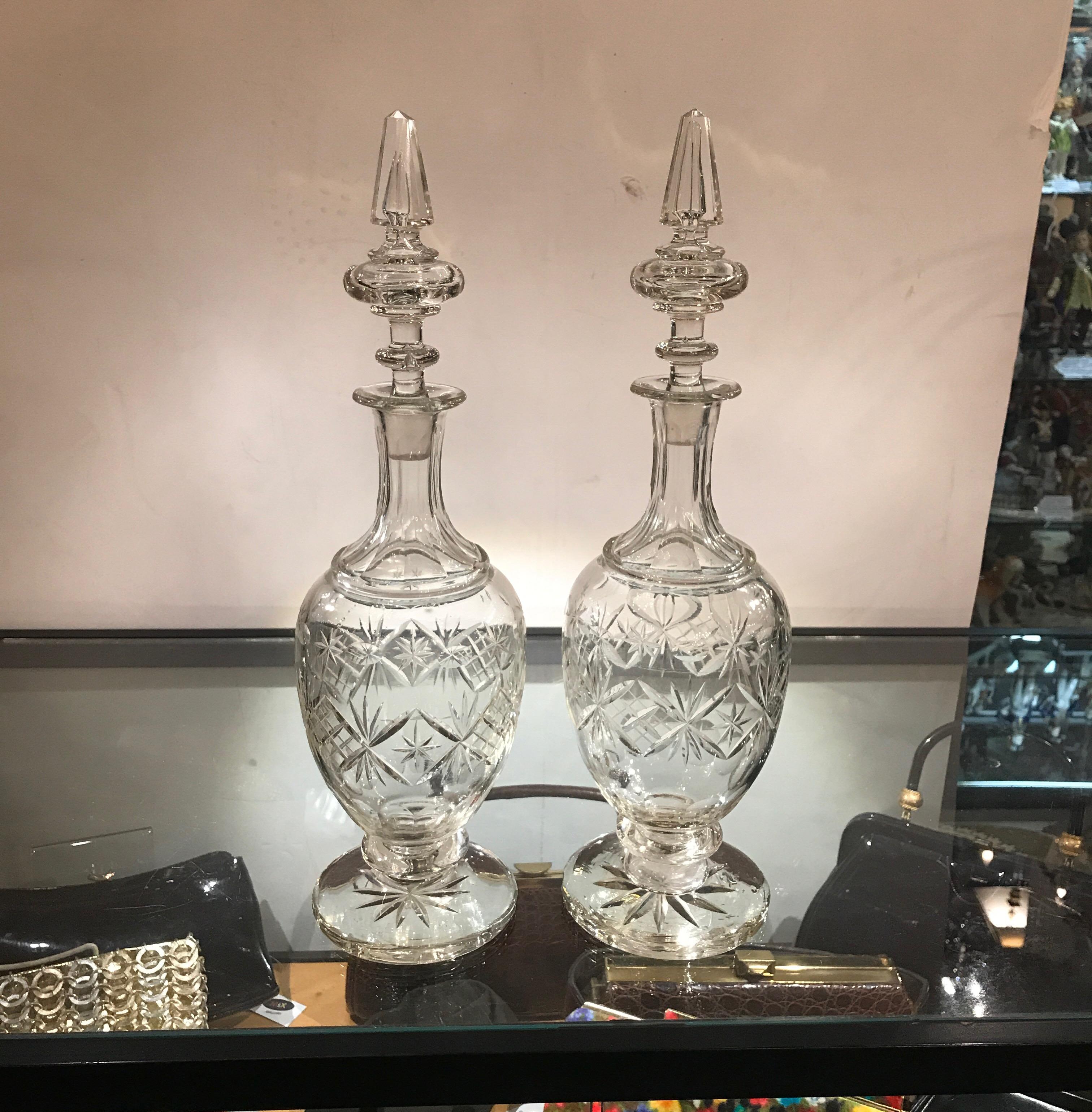 A pair of 19th century European cut glass decanters with spire stoppers. The speared panel cut tops with bulbous cut glass bottles on pedestal bases.