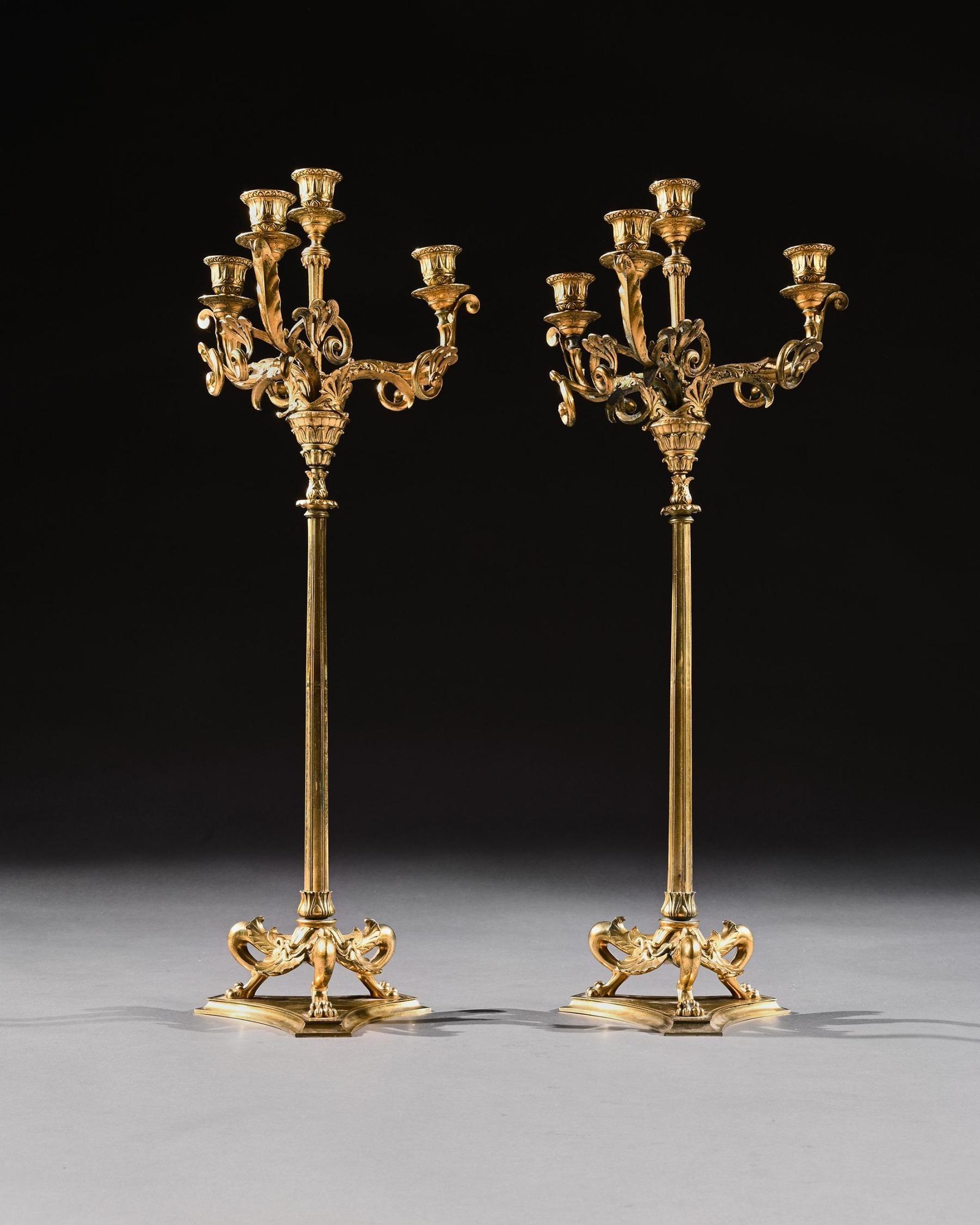 An elegant pair of gilt brass neoclassical Revival four light candelabra by Elkington and Co.

English, circa 1880.

The three leaf-cast scrolling branches enclosing a confirming scones above slender string stems with lappet-cast collars on