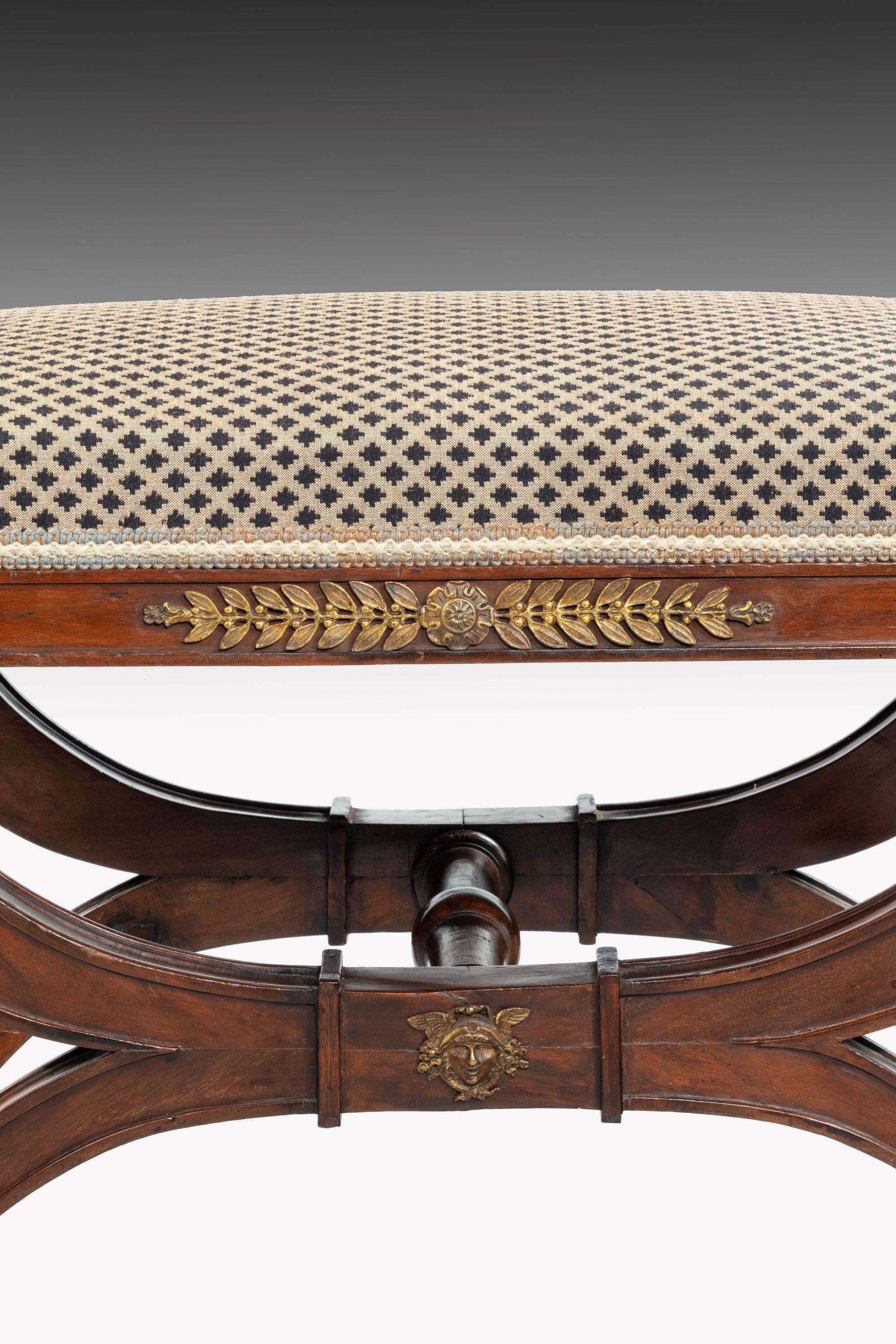 An extremely elegant pair of 19th century mahogany framed stools. On lyre supports retaining the original ormolu, which is now patinated.
 