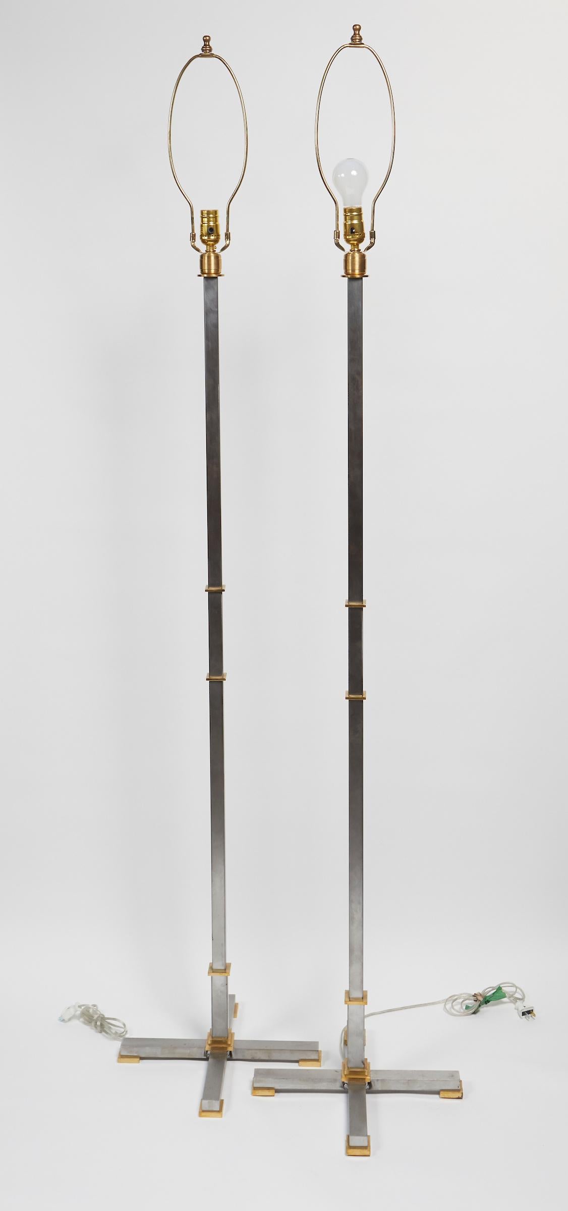 Elegant pair of brushed steal and solid brass floor lamps by Maison Jansen. Signed Jansen.