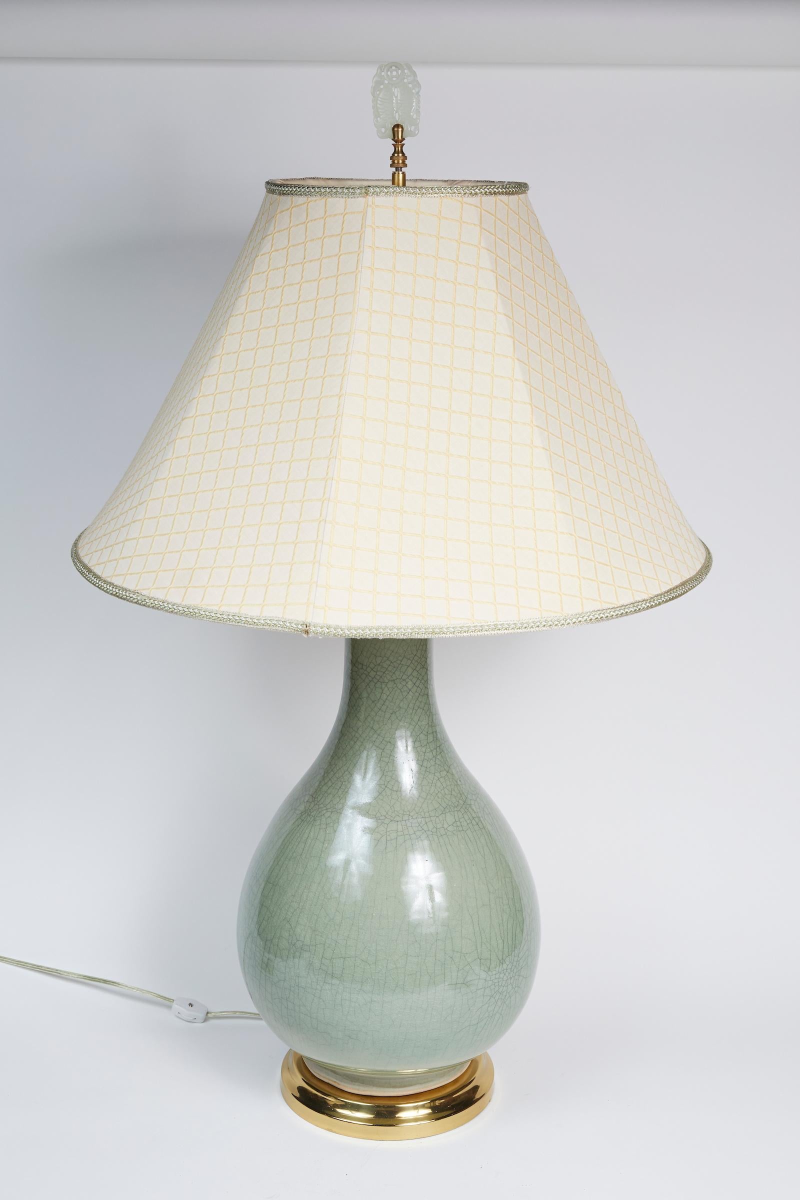Elegant pair of Celadon crackle table lamps with Asian finial and resting on a brass base.